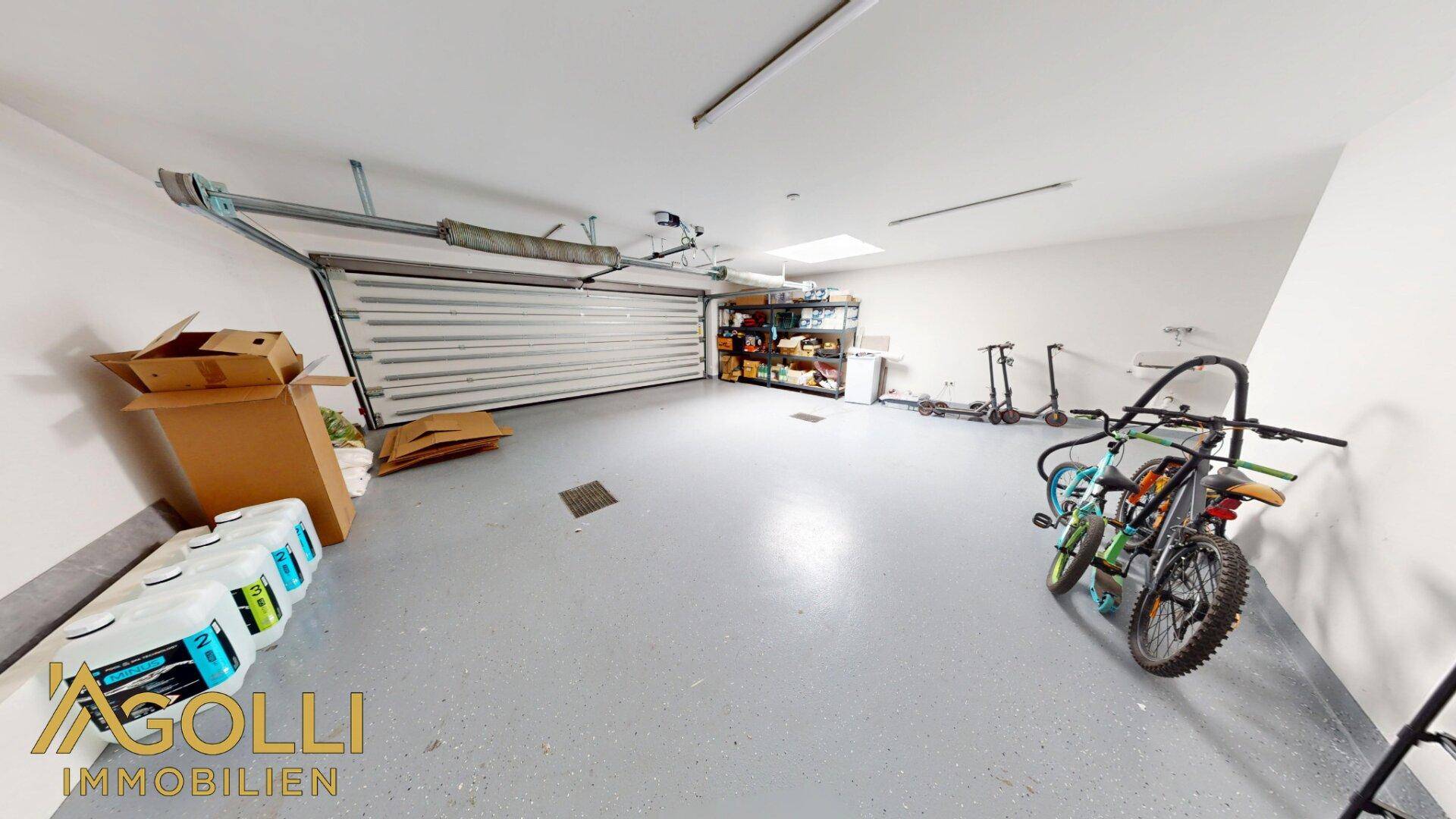 Geräumige Garage mit Rolltor, Stauraum und Platz für Fahrräder und Roller.