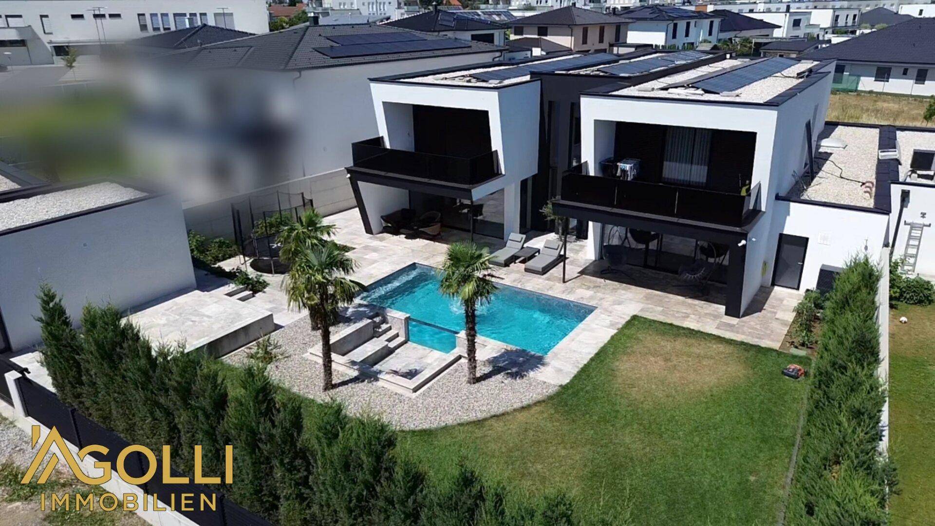Moderne Villa mit Pool, Garten und Solaranlagen auf dem Dach in einer Wohnsiedlung.