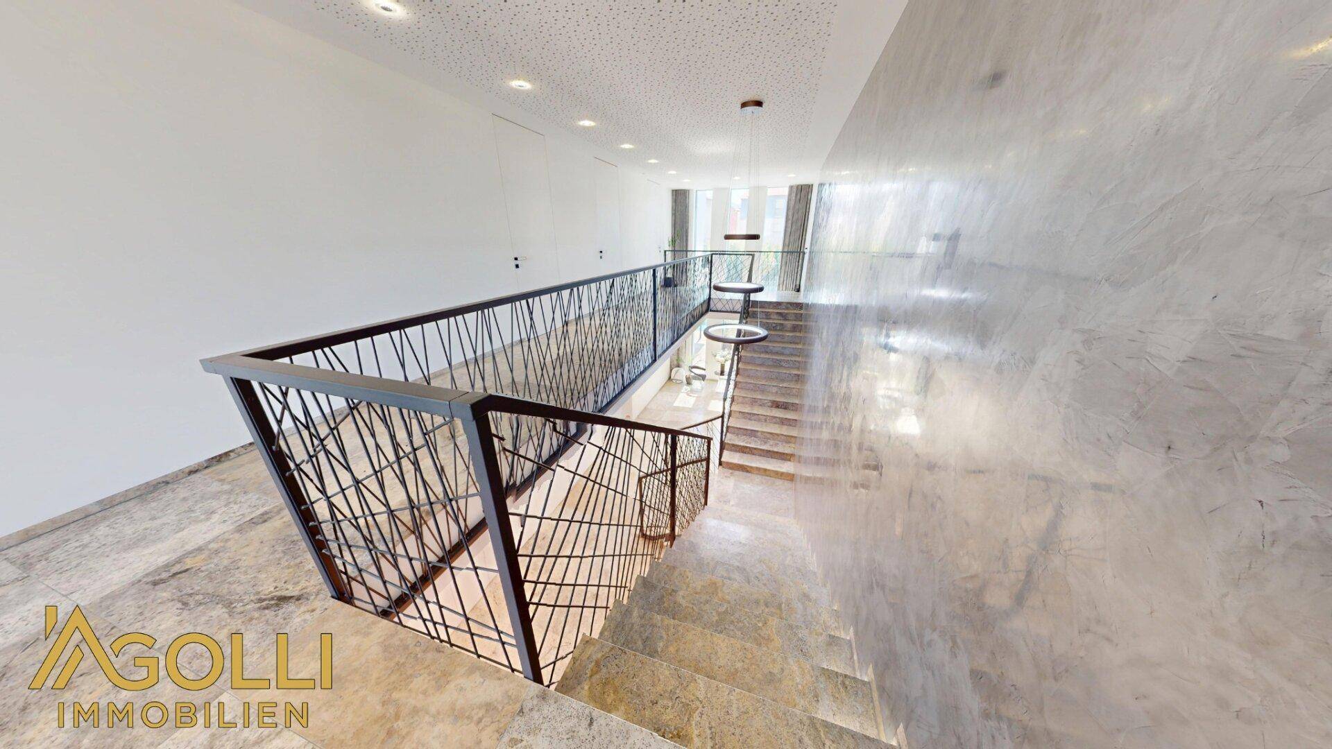 Blick von oben auf die Treppe mit beeindruckender Marmorwand und modernem Design.