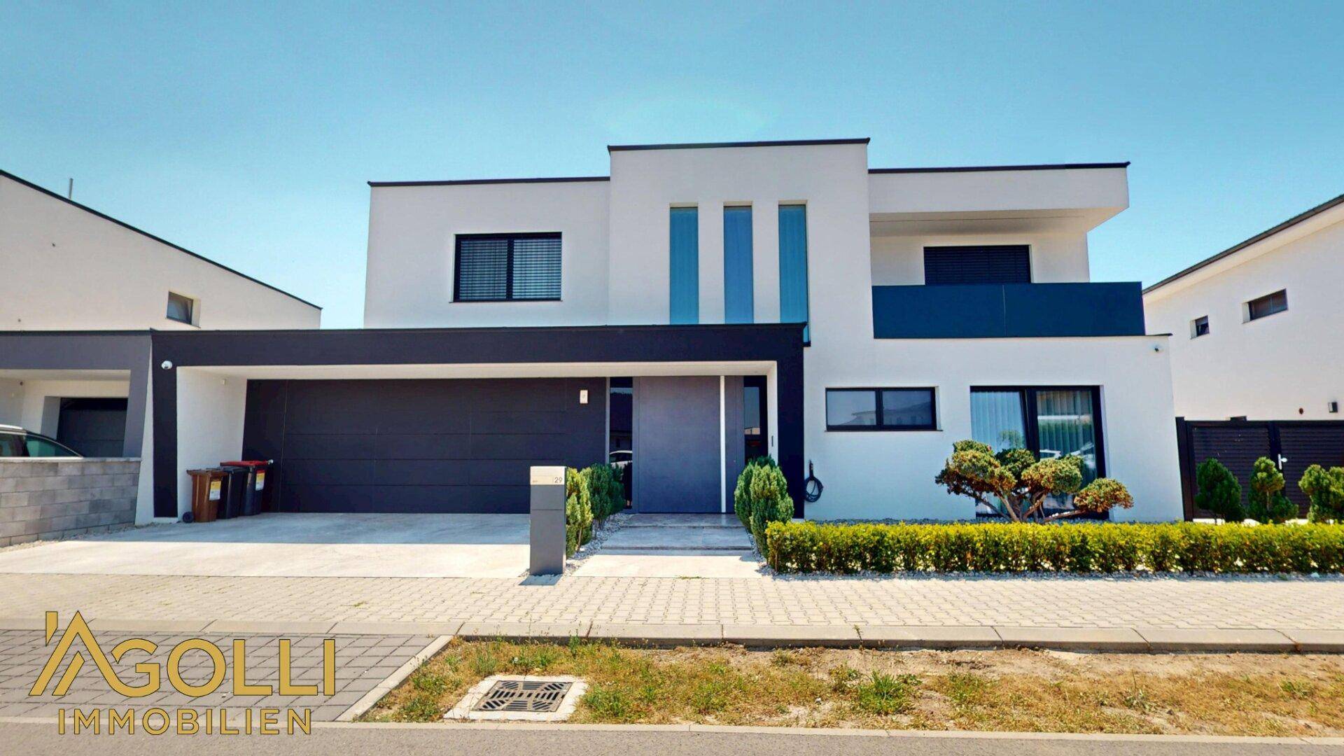 Ansicht der modernen Villa von vorne mit Garage und gepflegtem Vorgarten.
