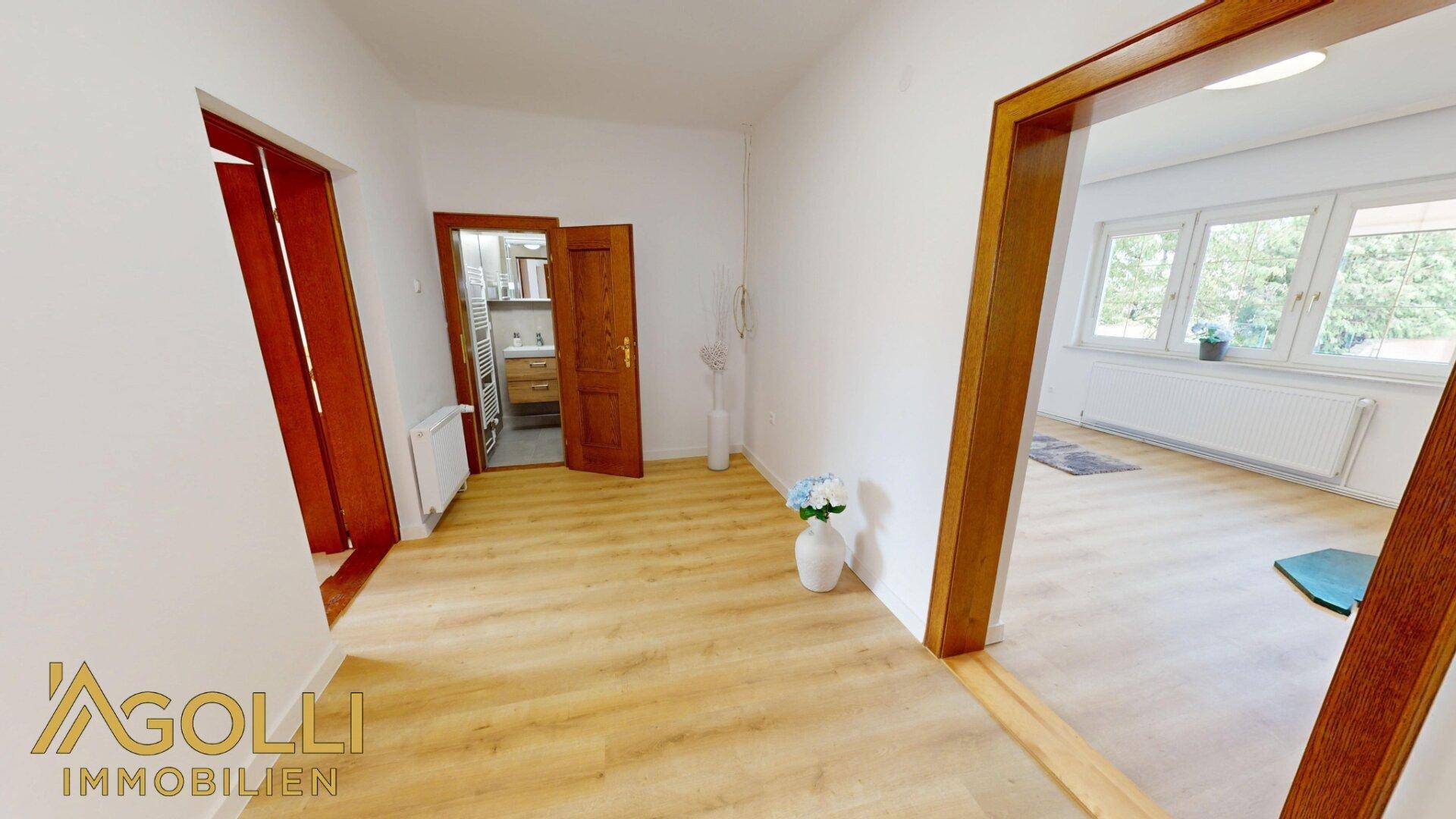 Heller Flur mit Laminatboden und Holztüren, der zu weiteren Räumen führt.