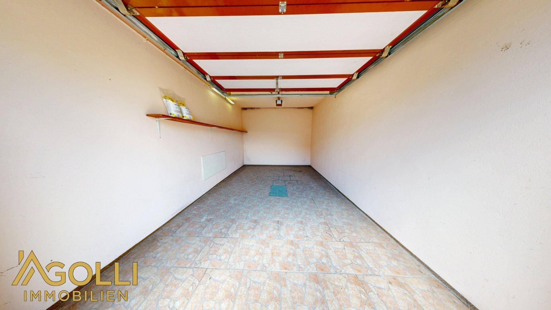 Geräumige Garage mit Fliesenboden und ausreichend Platz für ein Fahrzeug.