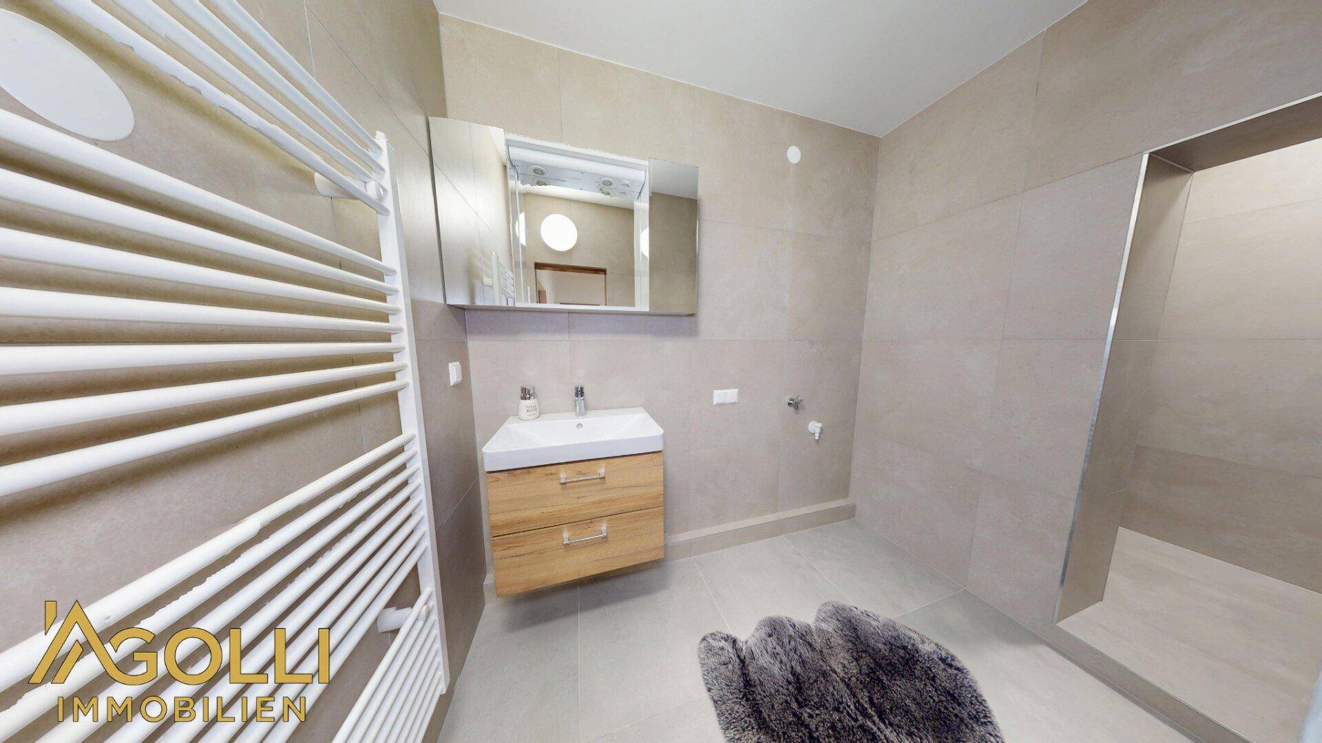 Modernes Badezimmer mit großen Fliesen, Einzelwaschbecken und begehbarer Dusche.