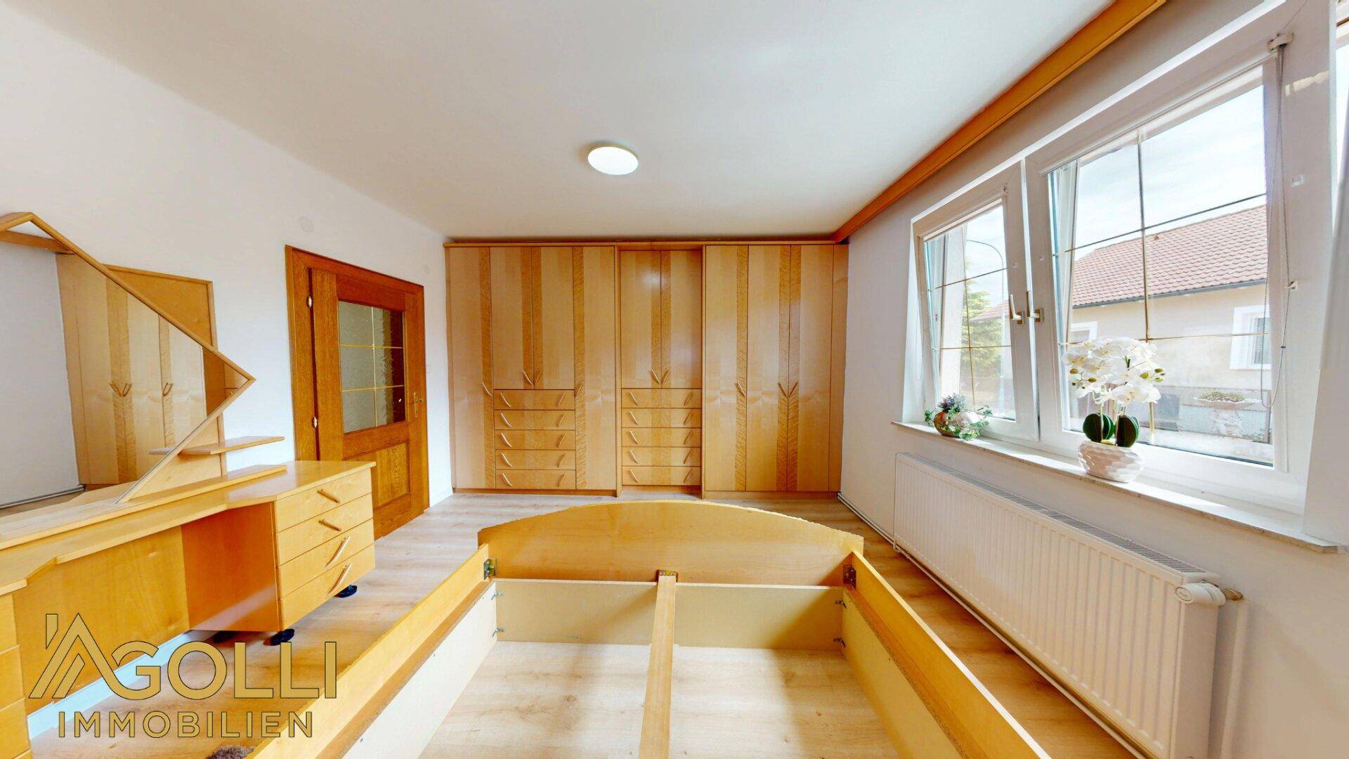 Helles Schlafzimmer mit Laminatboden, Einbauschränken und großen Fenstern.