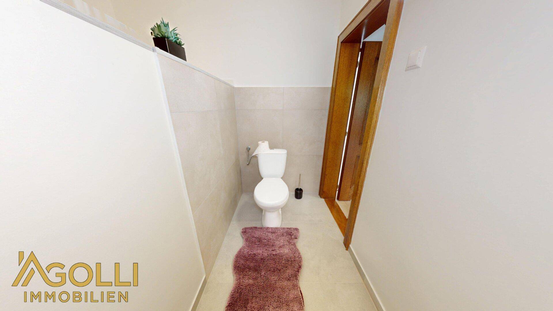 Kleines Gäste-WC mit Toilette und Fliesenboden in neutralen Farbtönen.