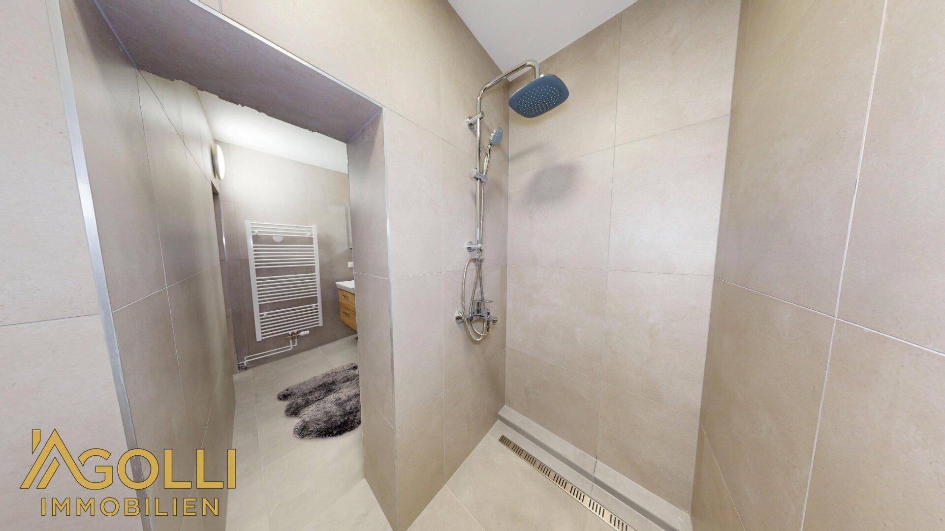 Geräumige, ebenerdige Dusche mit Regenduschkopf und modernen Fliesen im Badezimmer.