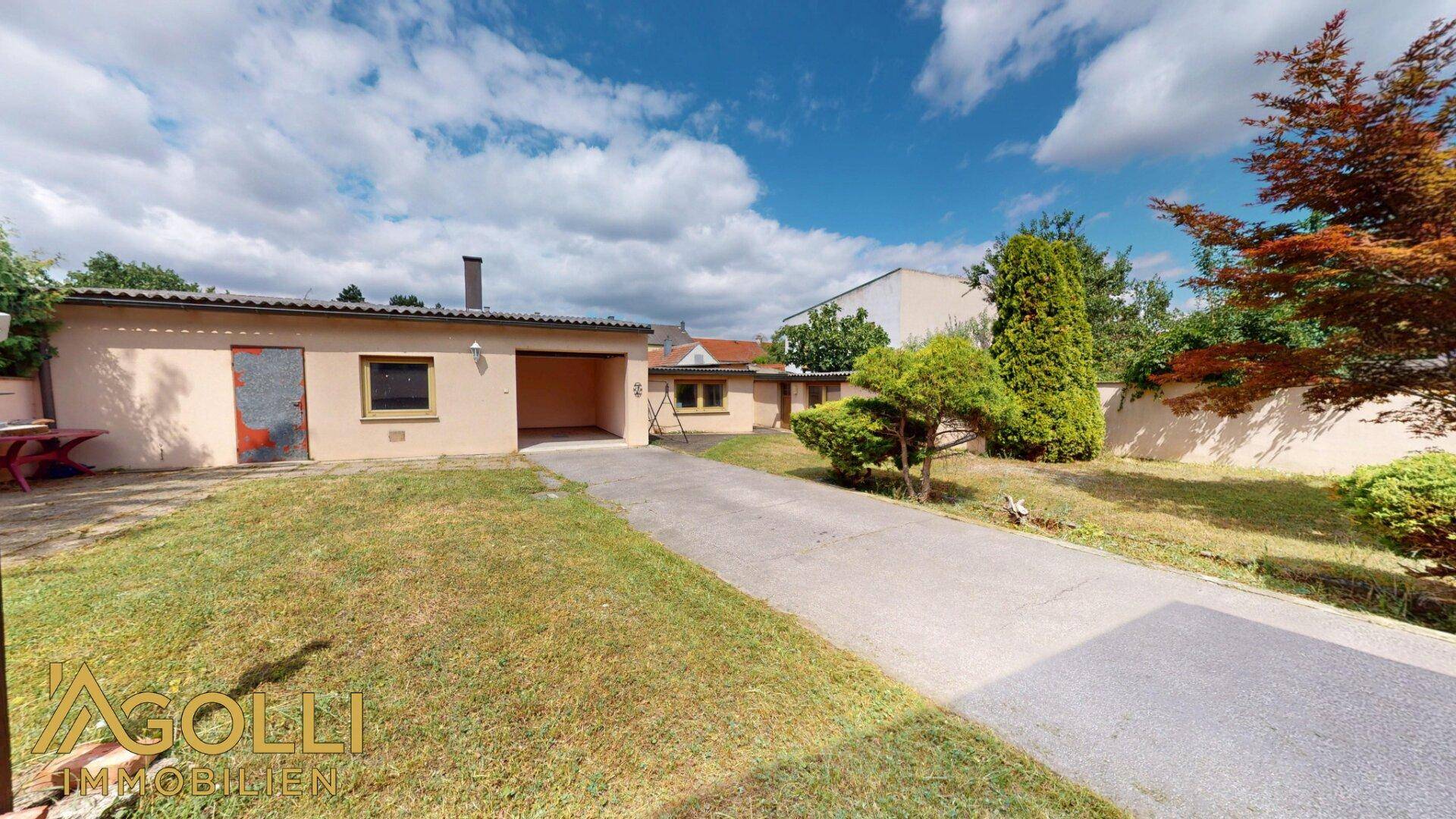 Hinterhof mit großem Rasen, Zufahrt und einer freistehenden Garage.