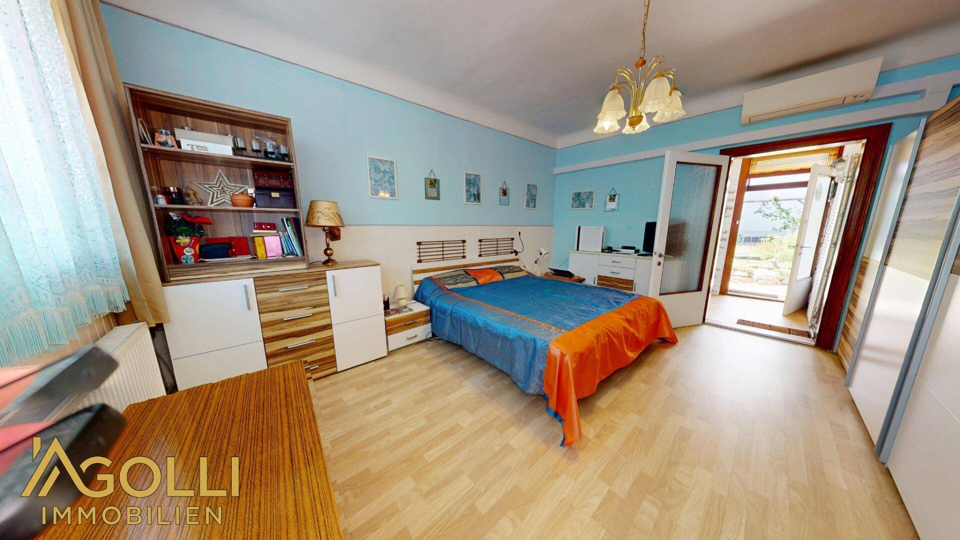 Geräumiges Schlafzimmer mit Doppelbett, hellblauen Wänden und Zugang zum Außenbereich.