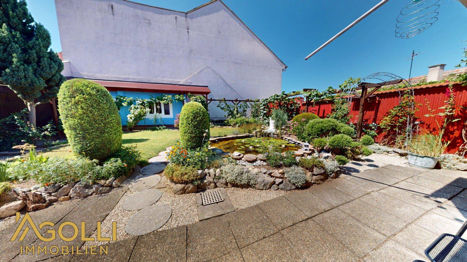 Gepflasterter Terrassenbereich mit Zierteich und dekorativen Gartenpflanzen.