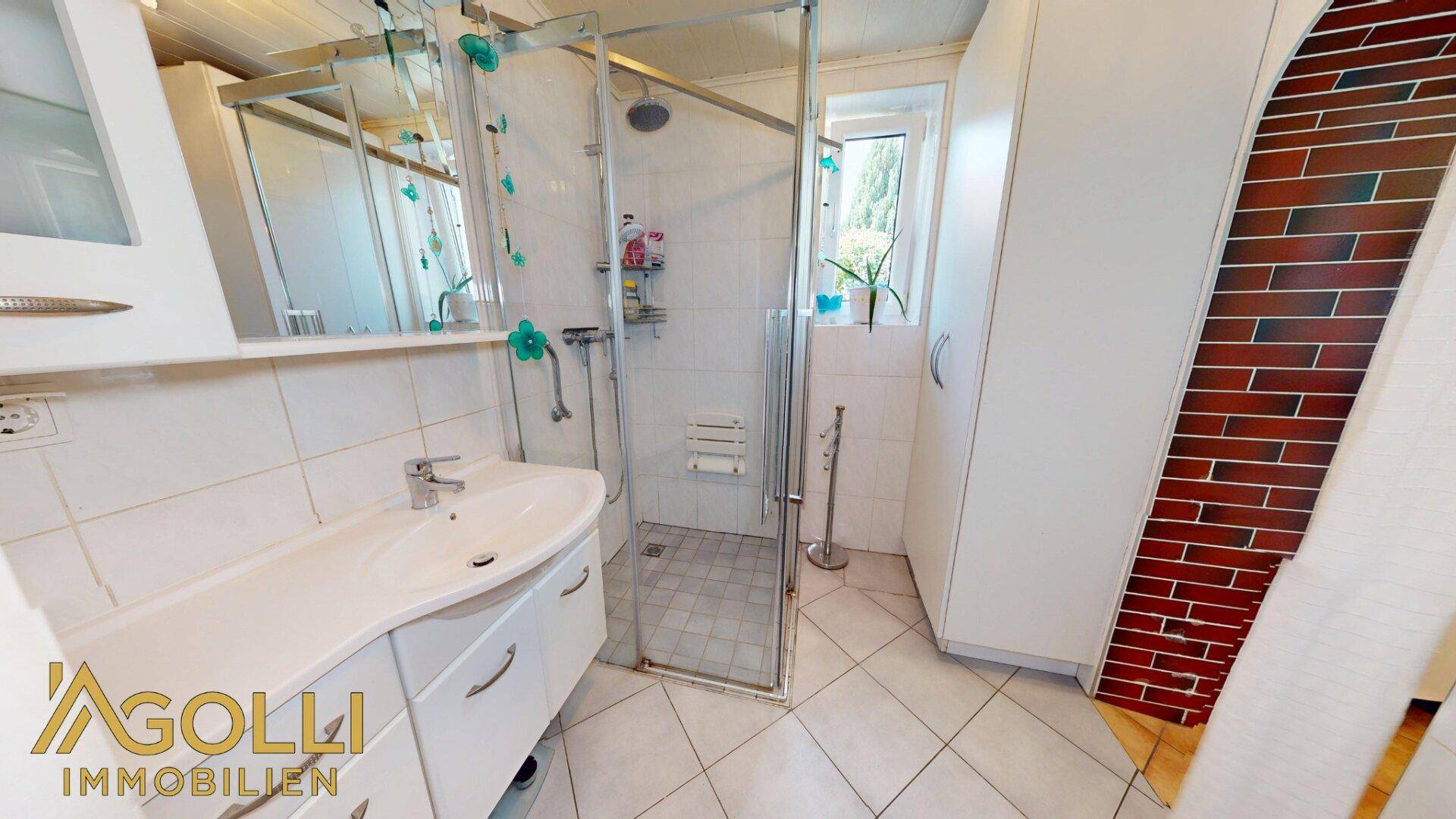Modernes Badezimmer mit Duschkabine, Einzelwaschbecken und hellen Fliesen.