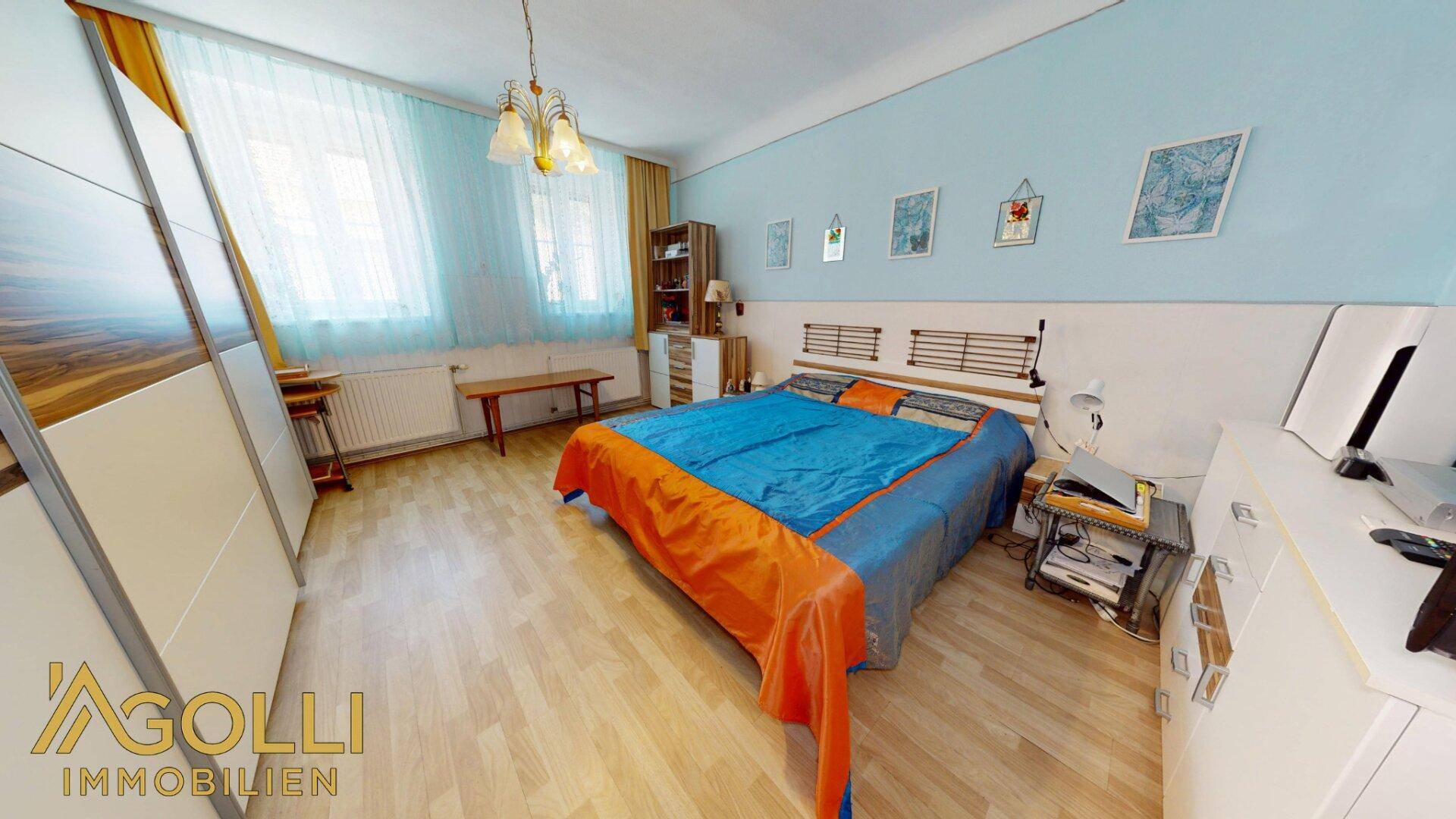 Helles Schlafzimmer mit Holzboden, großem Fenster und ausreichend Stauraum.