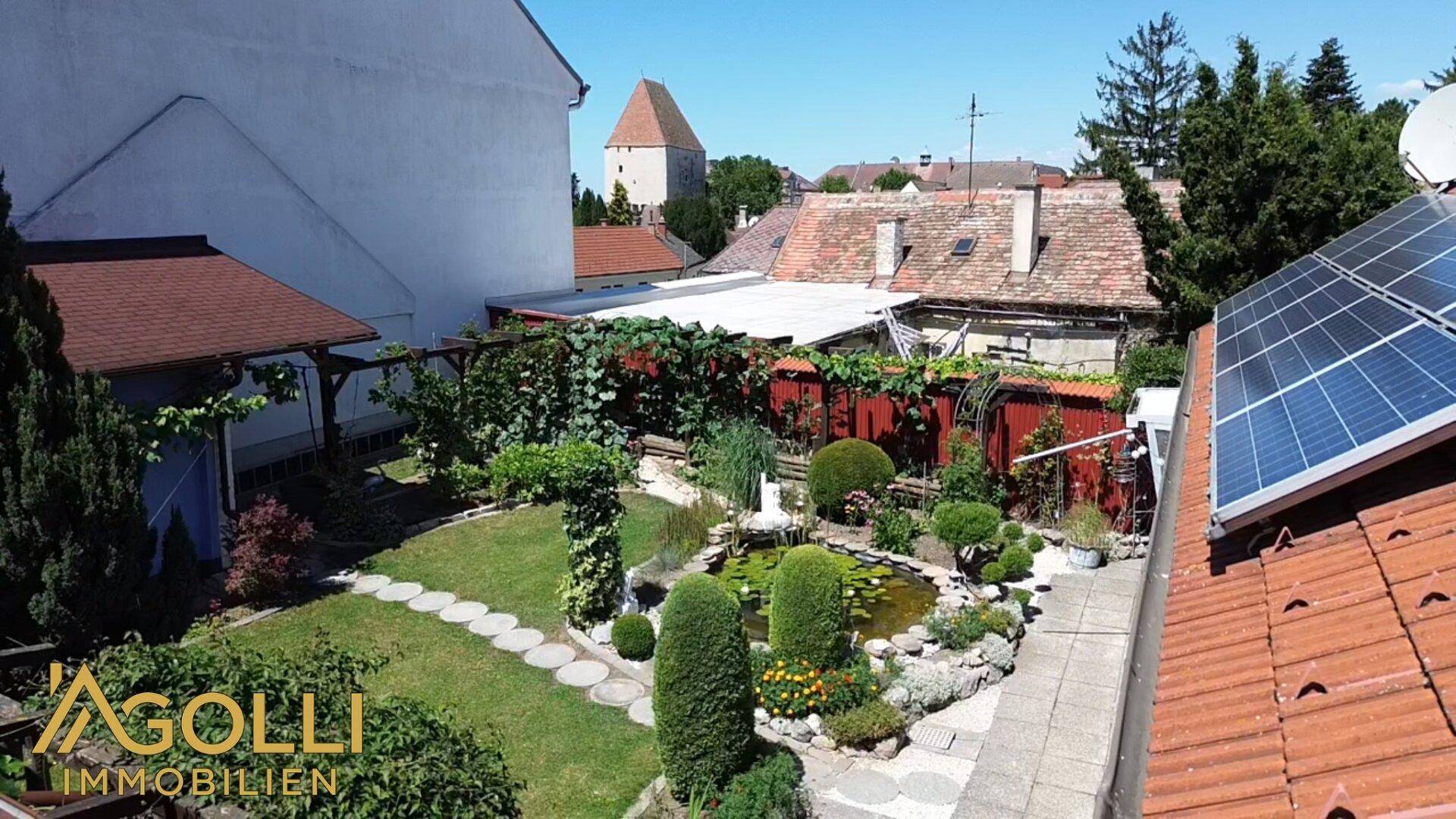 Vogelperspektive des Gartens mit Solaranlage auf dem Dach und Blick auf den historischen Turm.