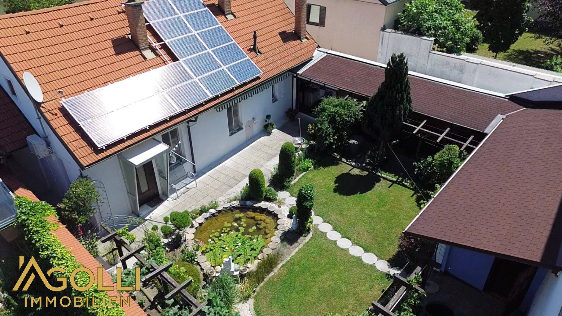 Draufsicht des Anwesens mit Haus, gepflegtem Garten und Solarpaneelen auf dem Dach.