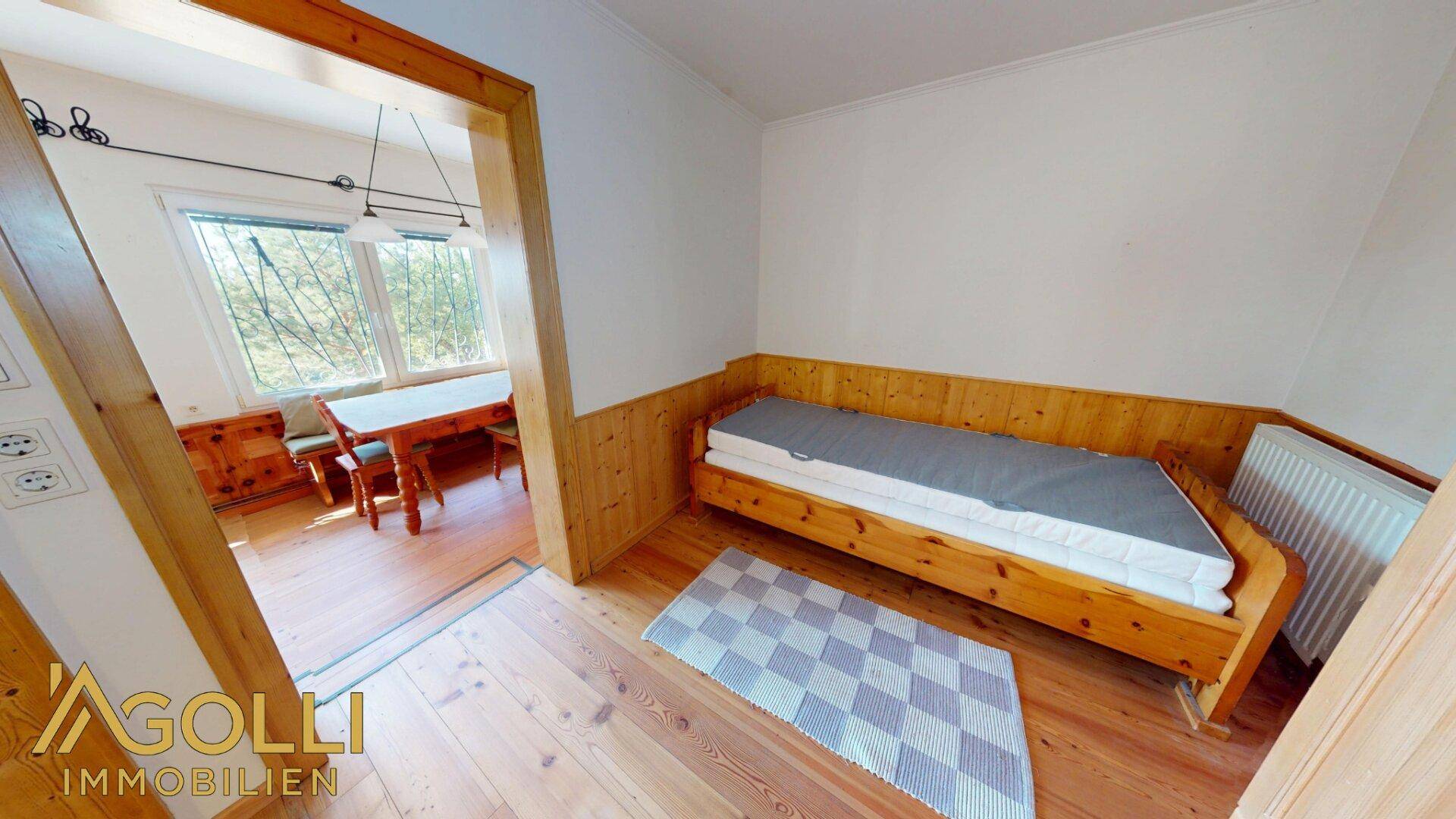 Gemütliches Schlafzimmer mit Holzboden und Zugang zu einem weiteren Raum.