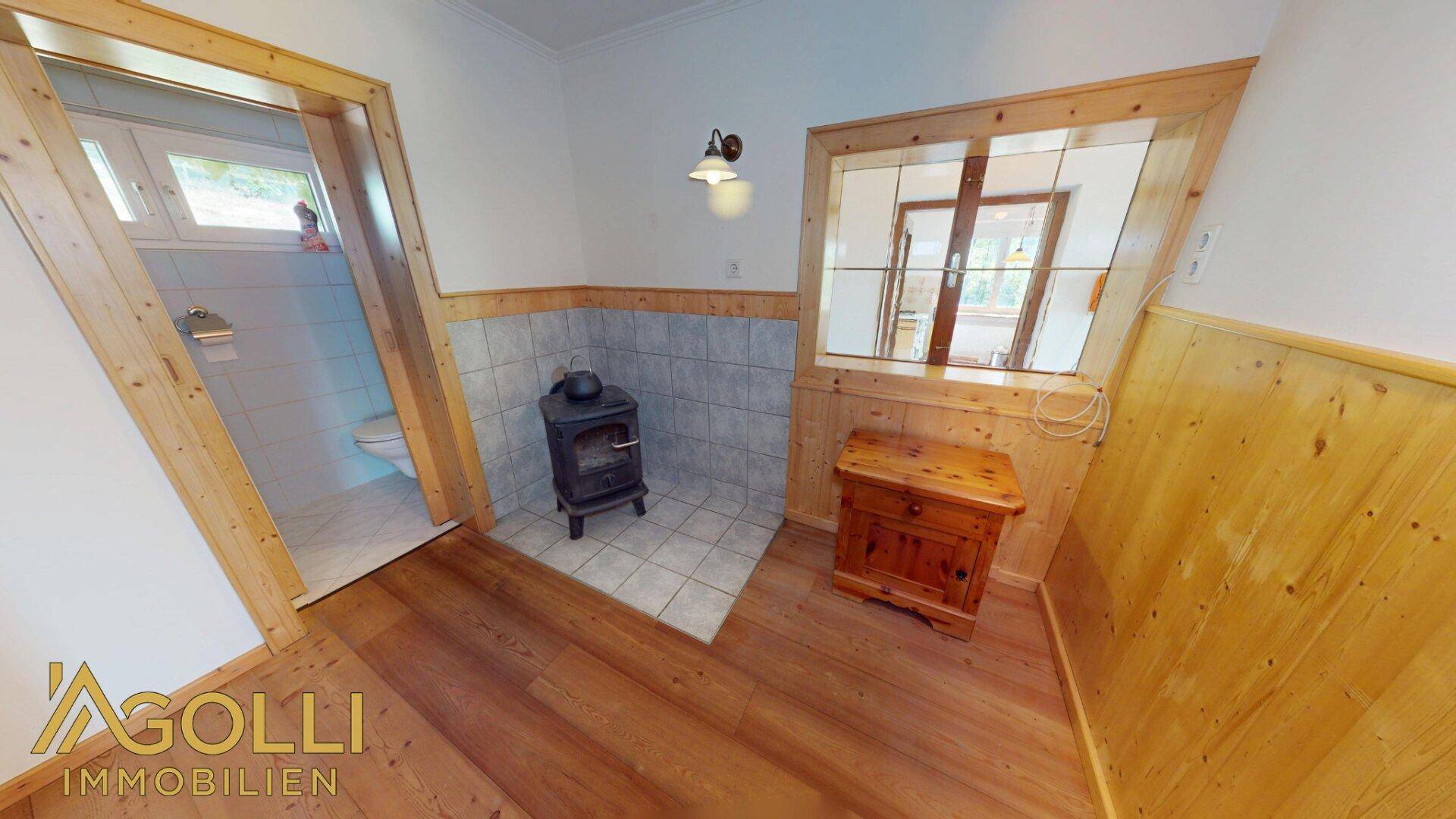 Kleiner Flurbereich mit Holzofen und Zugang zu einem Badezimmer.
