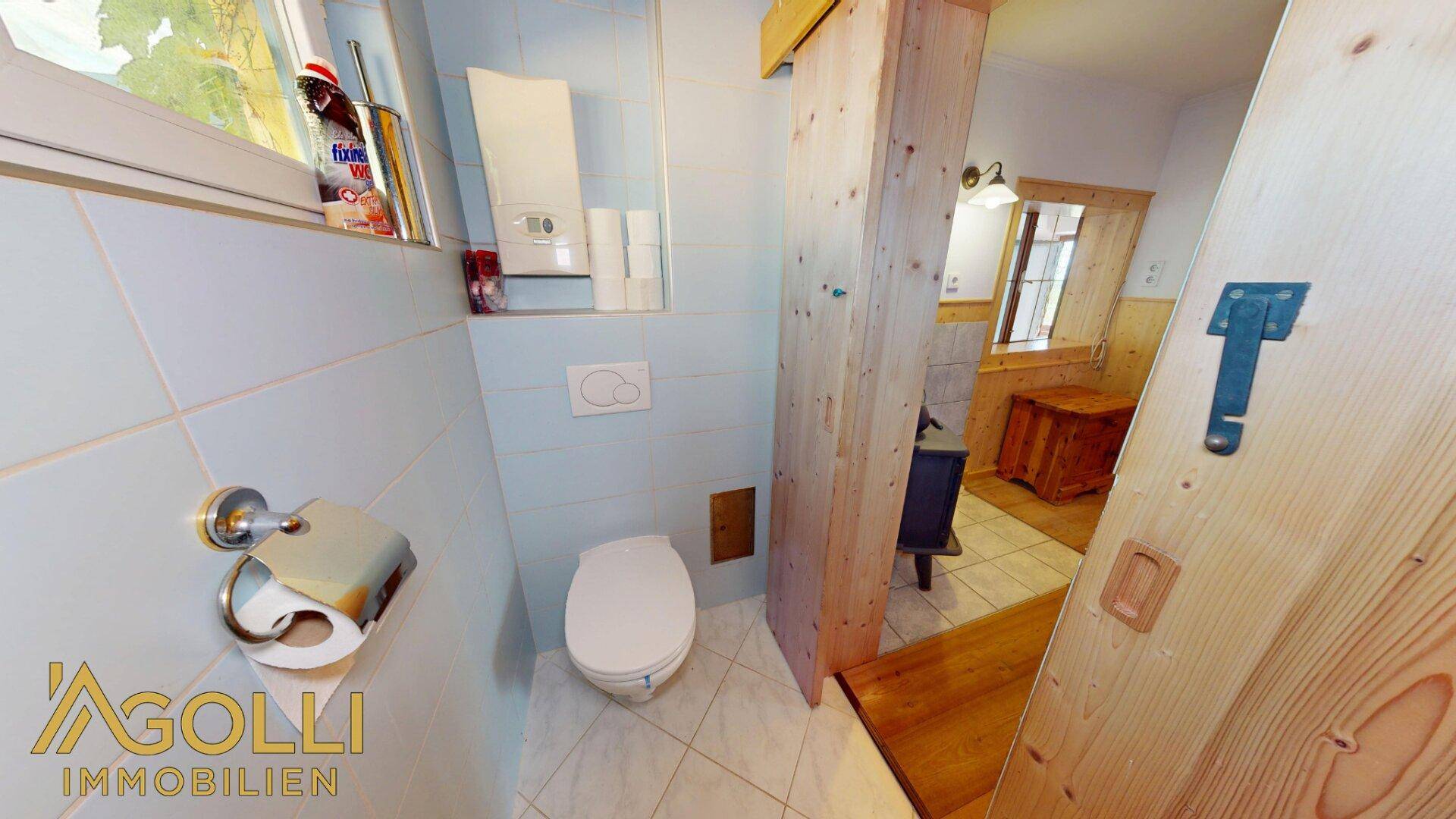 Separate Toilette mit Fenster und Zugang zu einem weiteren Raum.