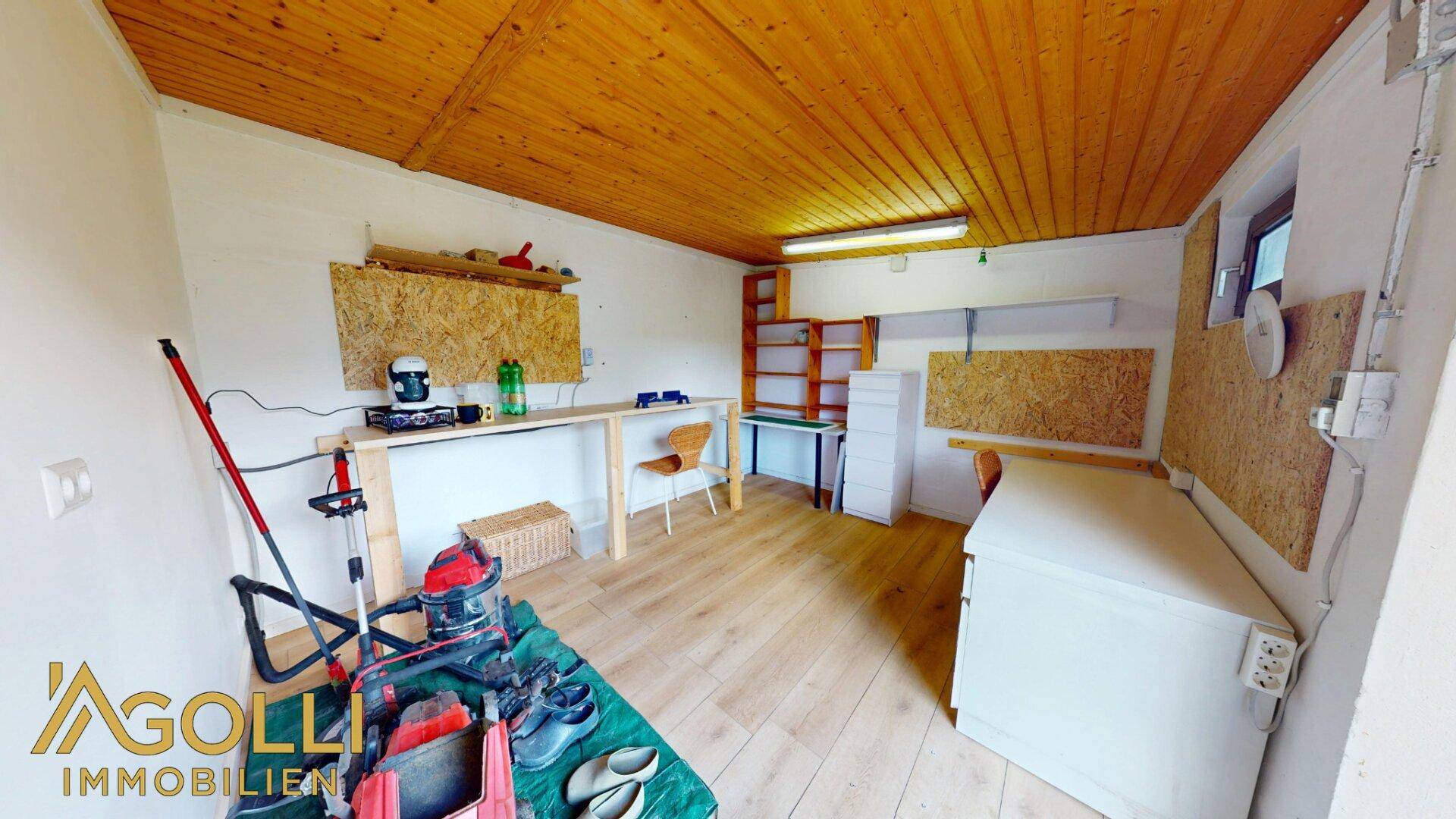Werkstatt im Gartenhaus mit Holzdielenboden, Holzdecke und Arbeitsflächen.