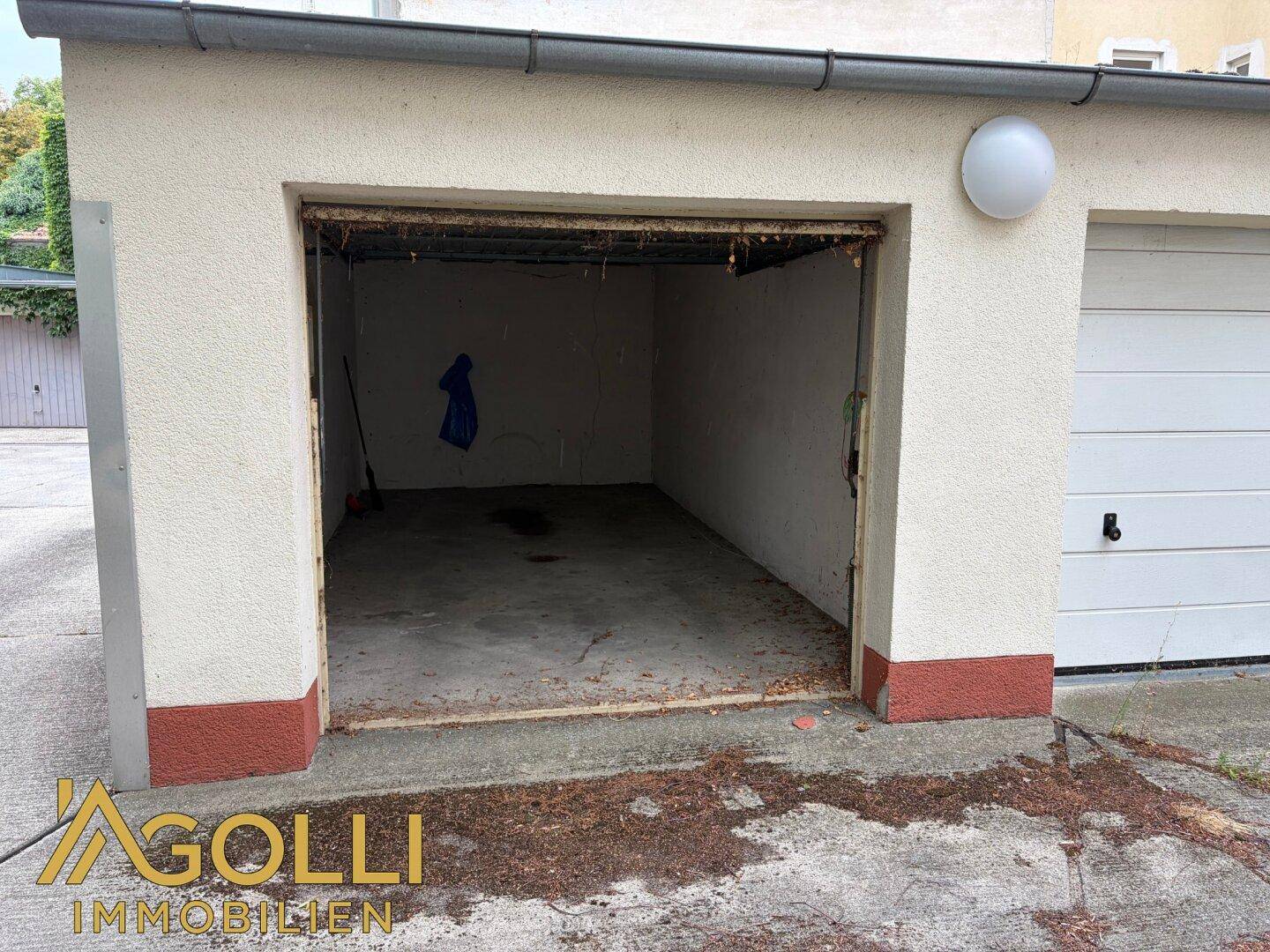 Offene Einzelgarage mit Betonboden und sichtbaren Innenwänden, bereit zur Nutzung.