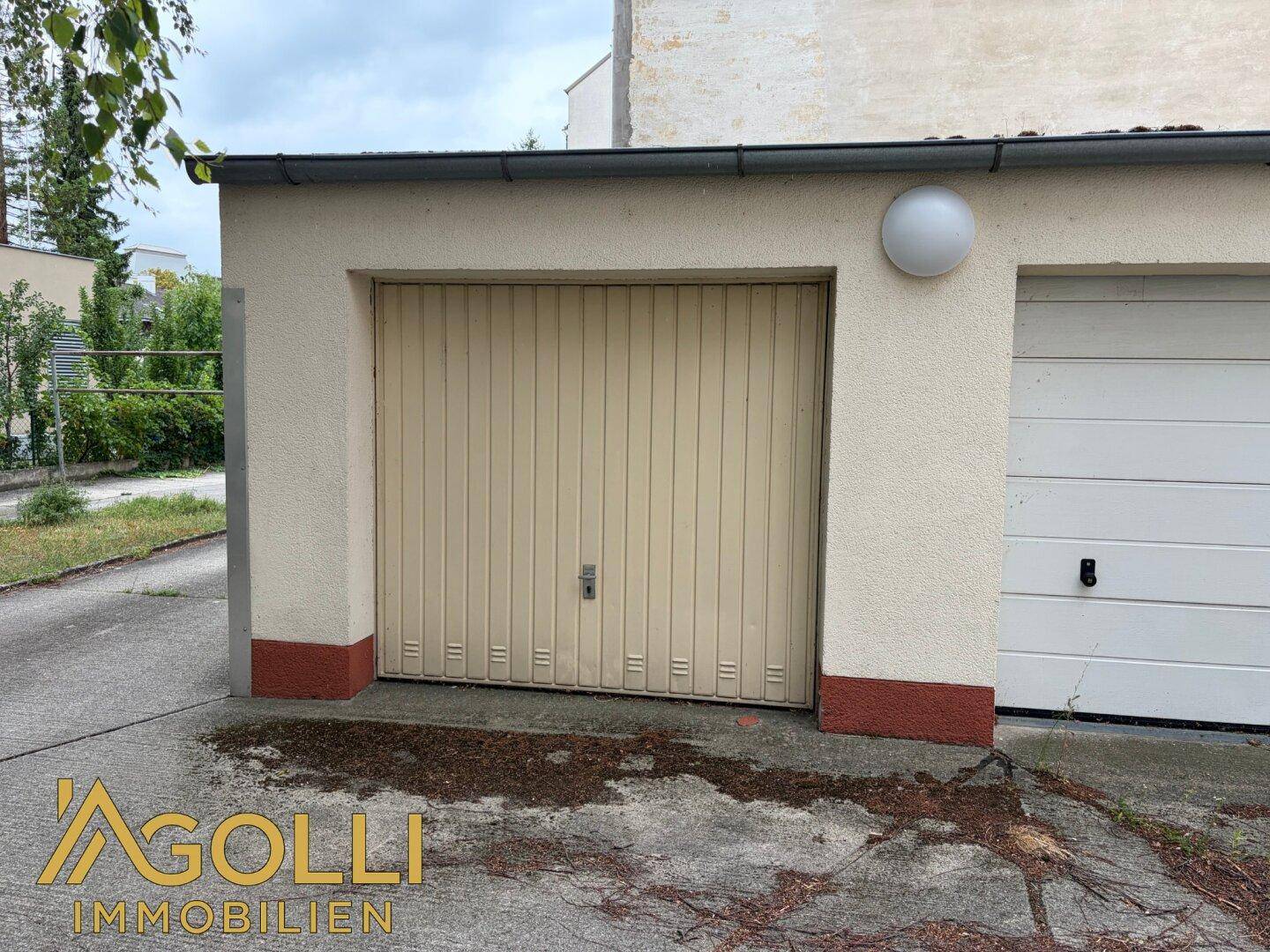 Einzelgarage mit geschlossenem Tor und Putzfassade, Teil einer Garagenreihe.