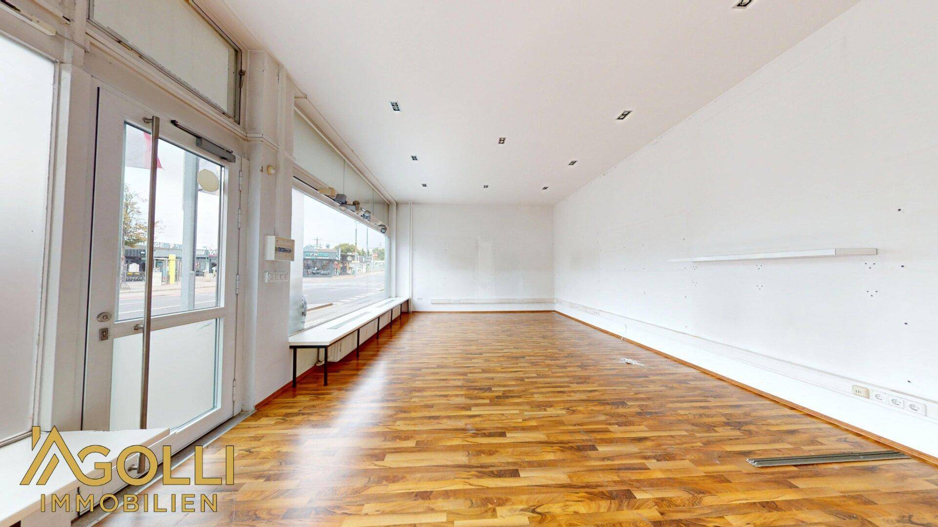 Eingangsbereich des Verkaufsraums mit Glastür und großen Schaufenstern zur Straße.