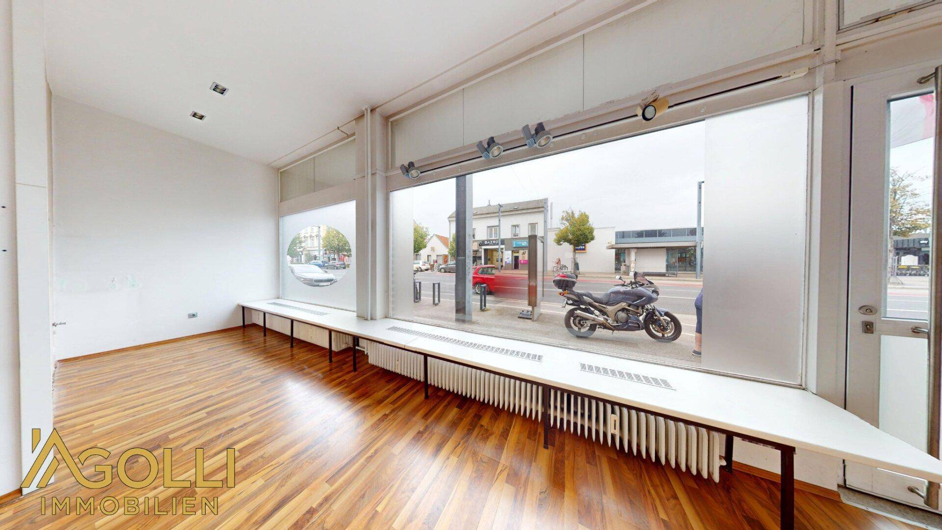 Verkaufsraum mit breiter Fensterfront, Heizkörpern darunter und Blick auf die Straße.