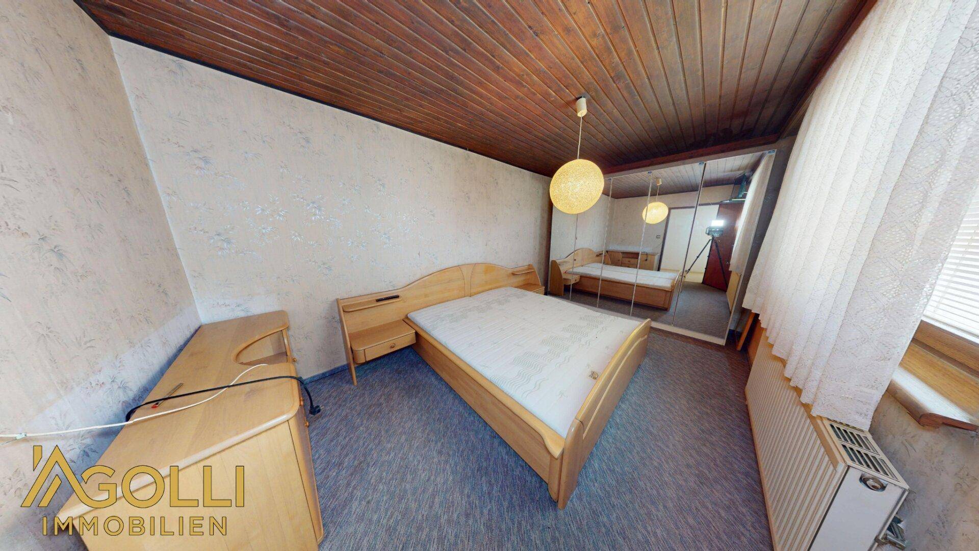 Schlafzimmer mit Holzbett, Nachttischen und einem großen Spiegelschrank.