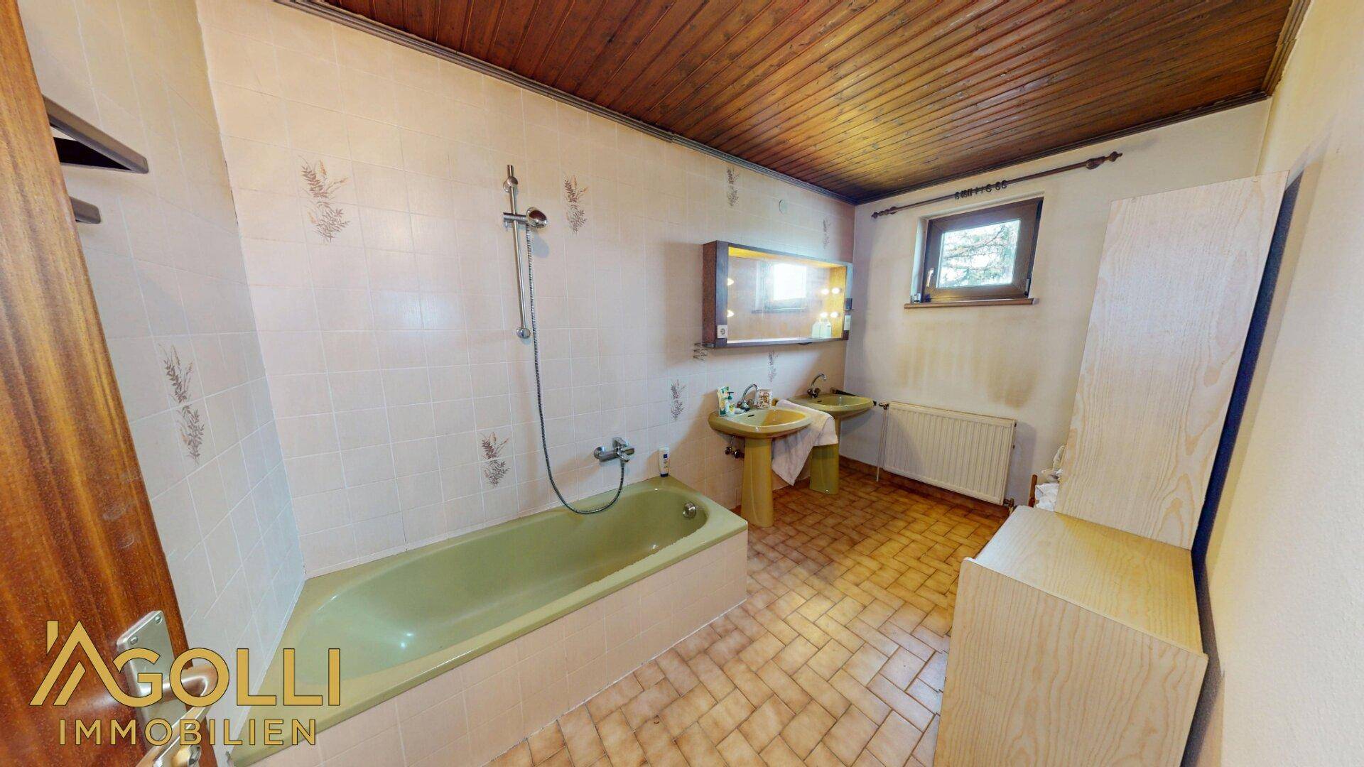 Badezimmer mit grüner Badewanne, gefliesten Wänden und einer Holzdecke.