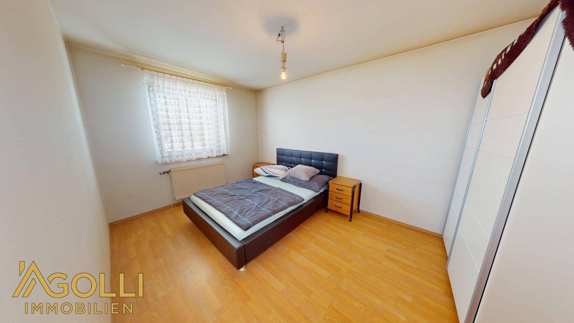 Schlafzimmer mit Doppelbett, weißem Kleiderschrank und hellem Holzboden.