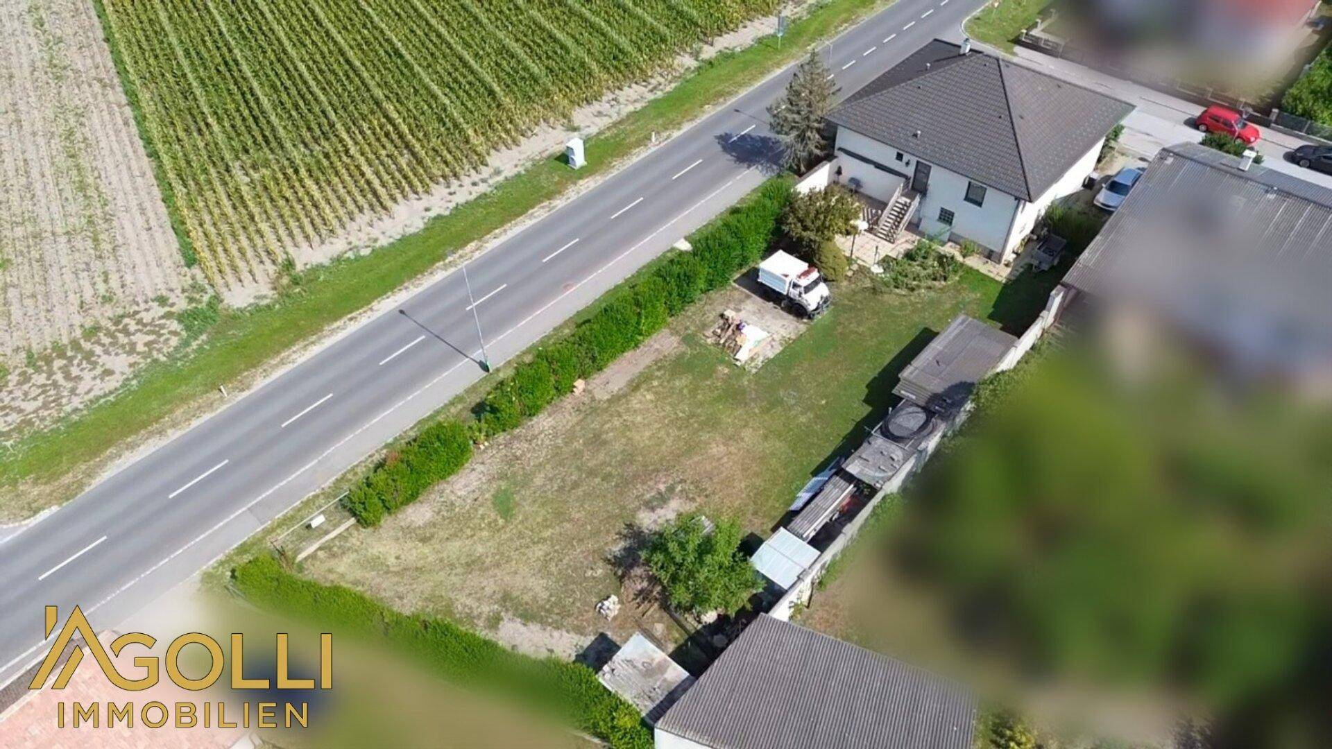 Luftaufnahme eines Hauses mit angrenzendem Grundstück, Straße und landwirtschaftlichen Feldern.