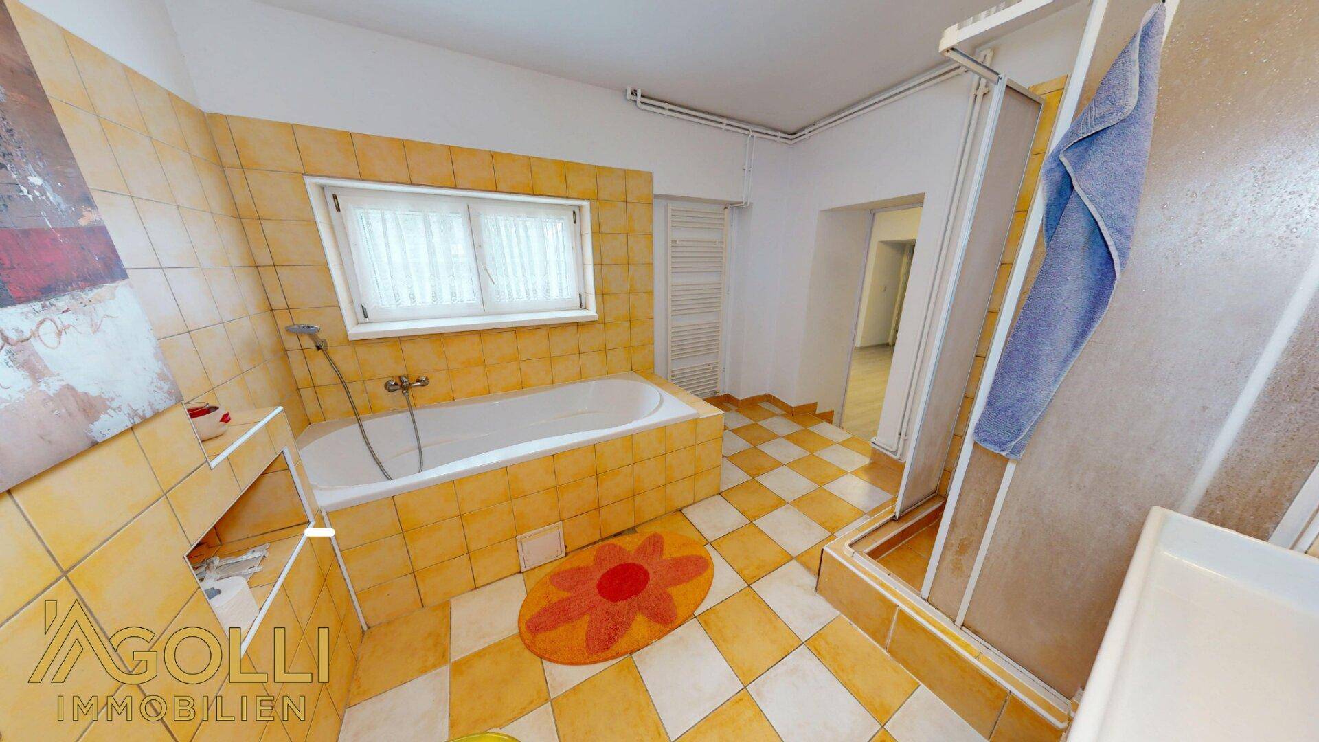 Badezimmer mit gelben Fliesen, Badewanne und separater Duschkabine.