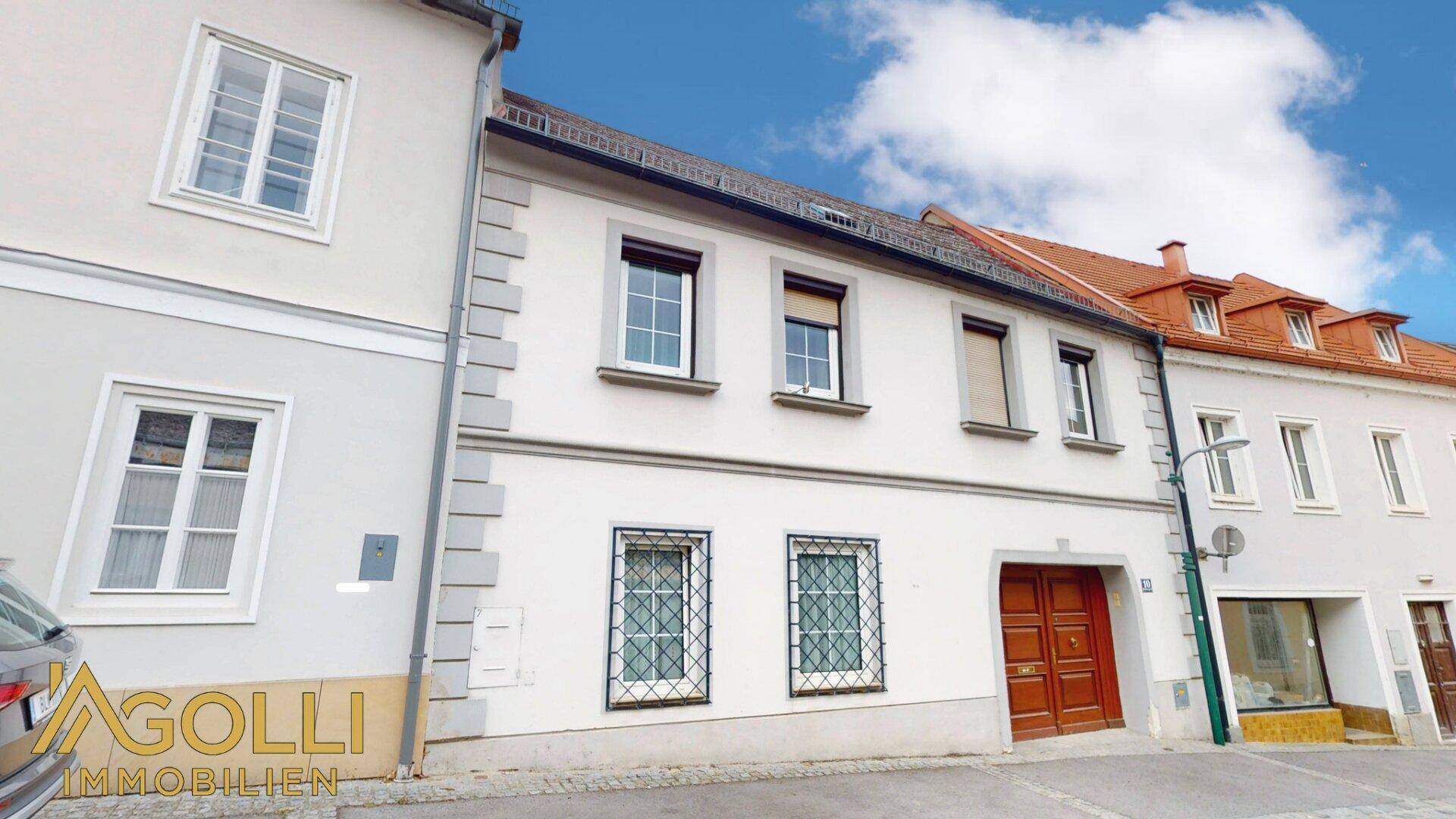 Fassade eines charmanten Stadthauses mit traditionellen Fenstern und einem Holztor.
