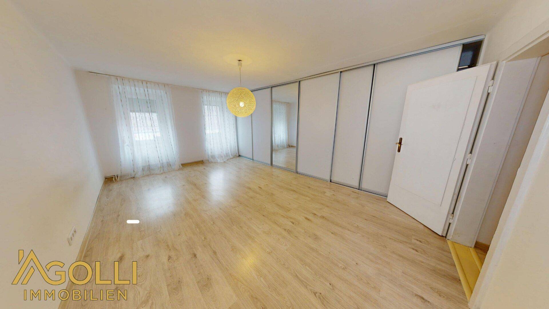 Helles Schlafzimmer mit Laminatboden und Spiegelschränken, bereit zur individuellen Gestaltung.