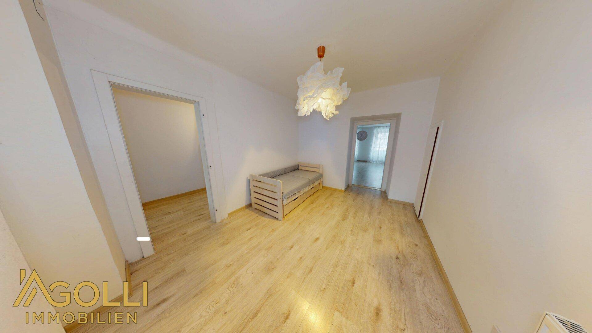 Helles Zimmer mit Laminatboden und einfacher Einrichtung, ideal als Schlaf- oder Gästezimmer.