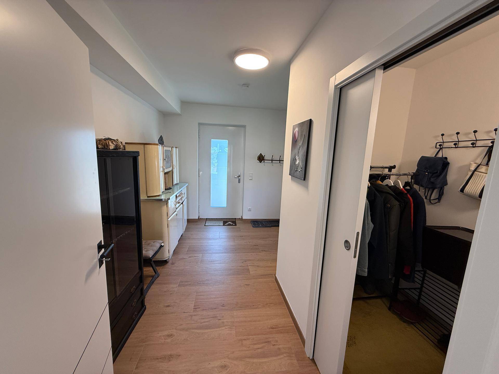 Heller Eingangsbereich mit Garderobe, Holzboden und Zugang zu weiteren Räumen.