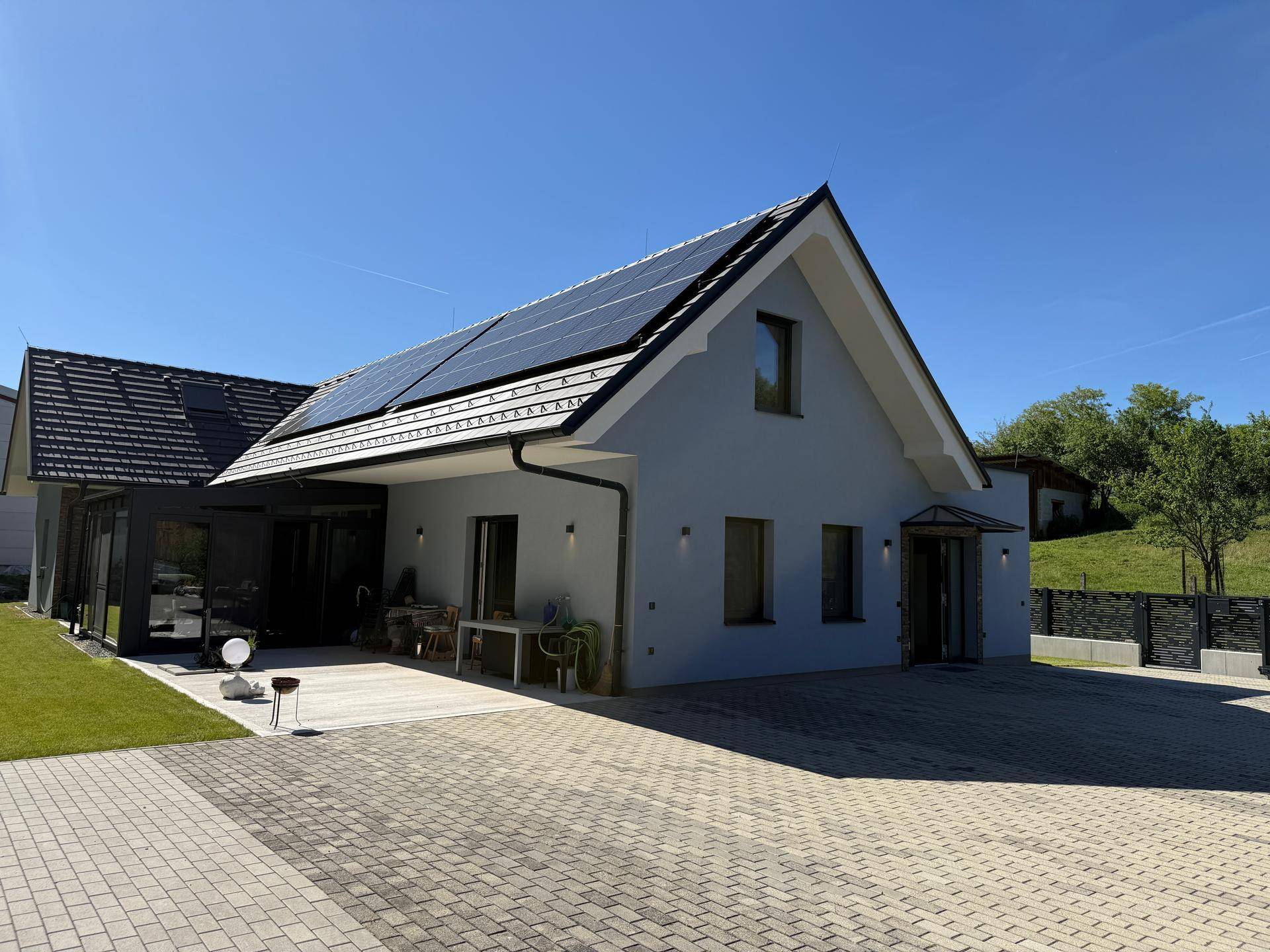 Neubau mit moderner Architektur, Solarpaneelen auf dem Dach und weitläufiger Außenanlage.