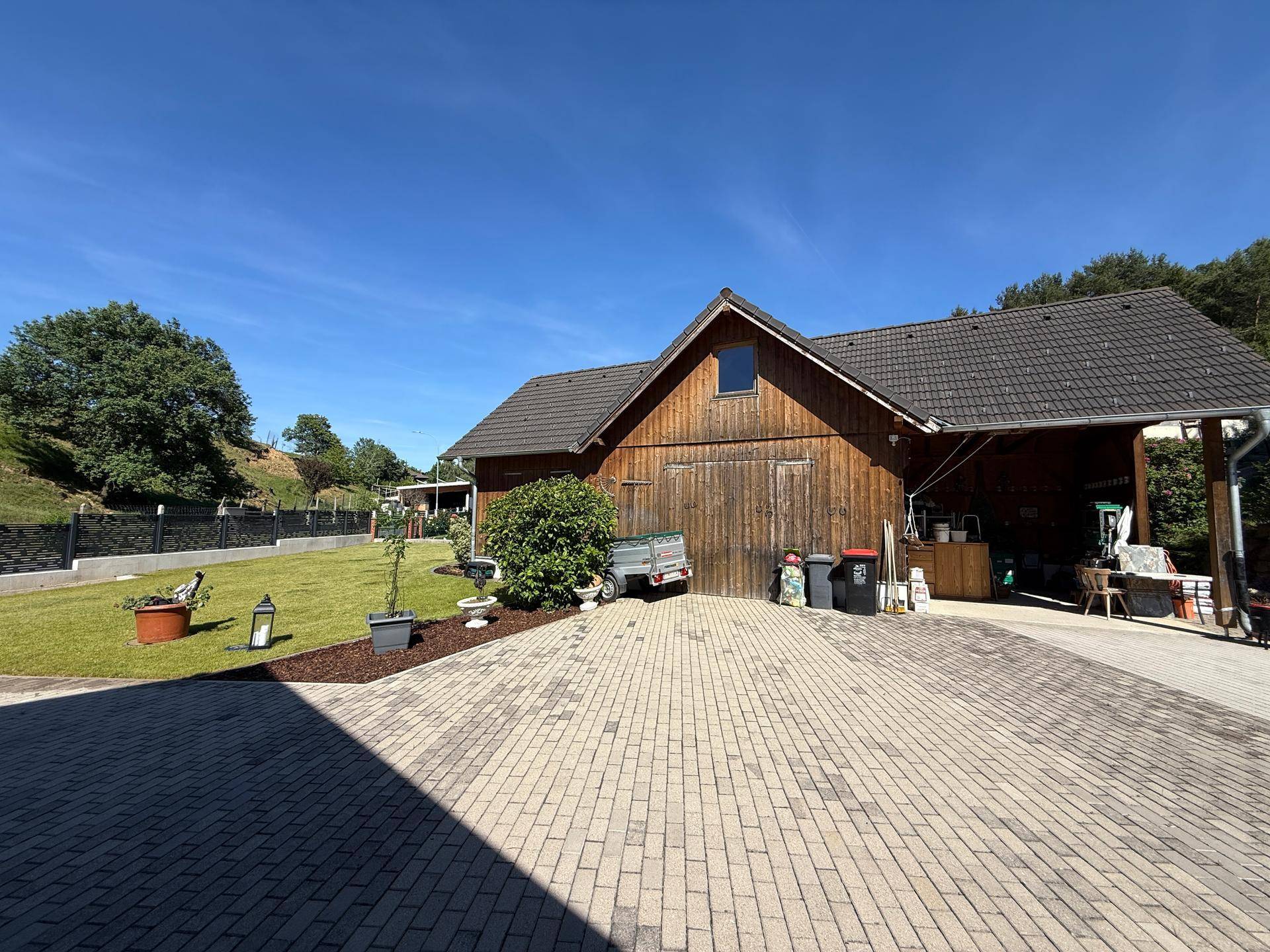 Rustikales Holzgebäude mit großem Vorplatz und angrenzender Rasenfläche in ländlicher Umgebung.