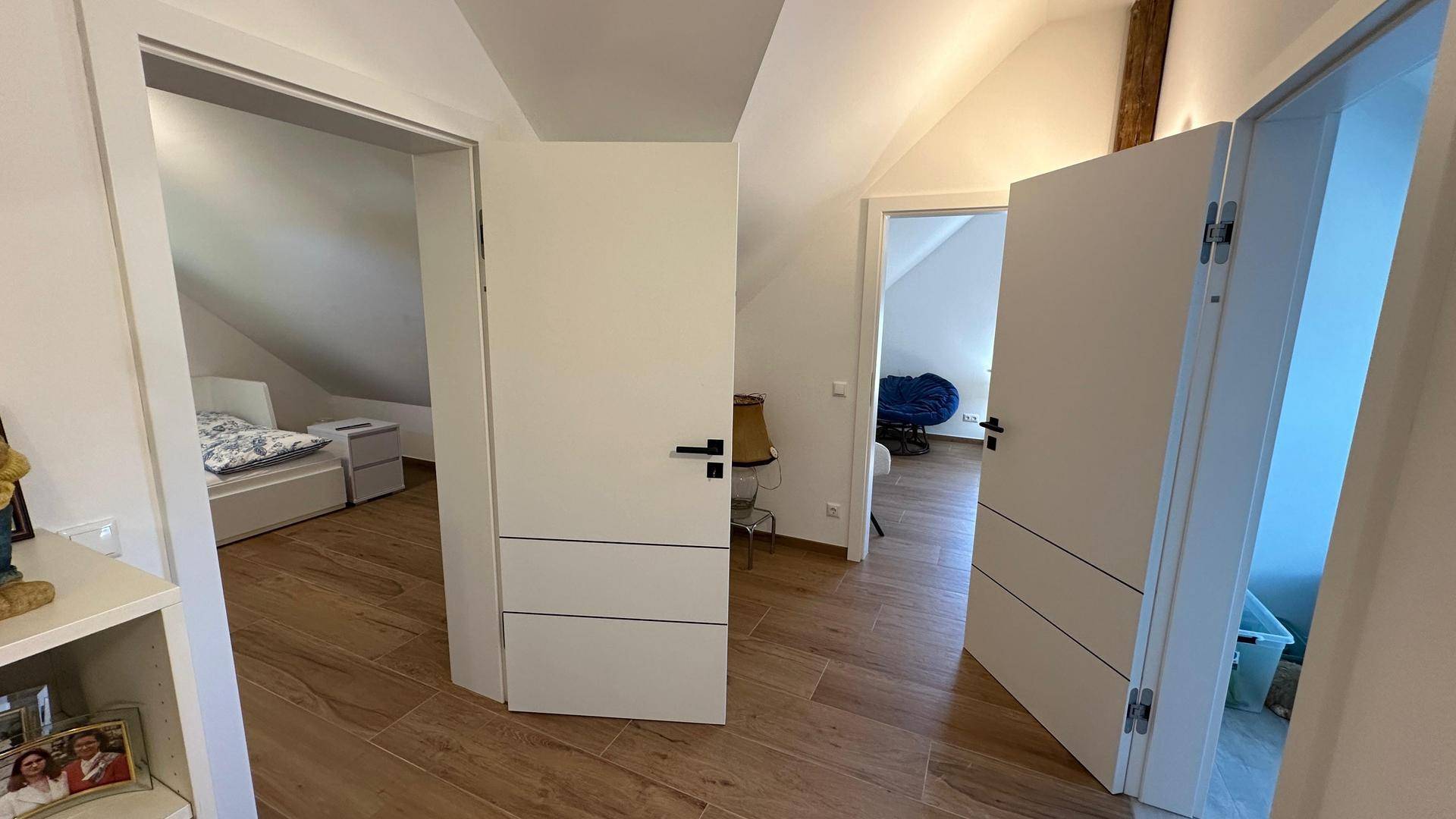 Heller Flur im Dachgeschoss mit Holzboden und Zugang zu mehreren Zimmern.
