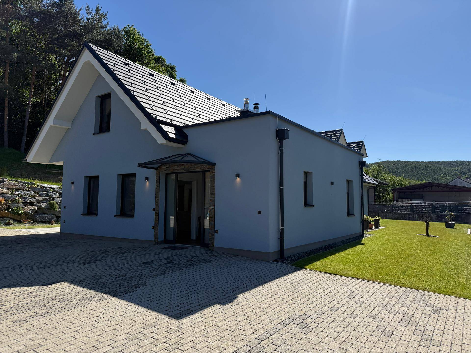 Freistehendes Einfamilienhaus mit Satteldach, Solaranlage und gepflasterter Zufahrt.