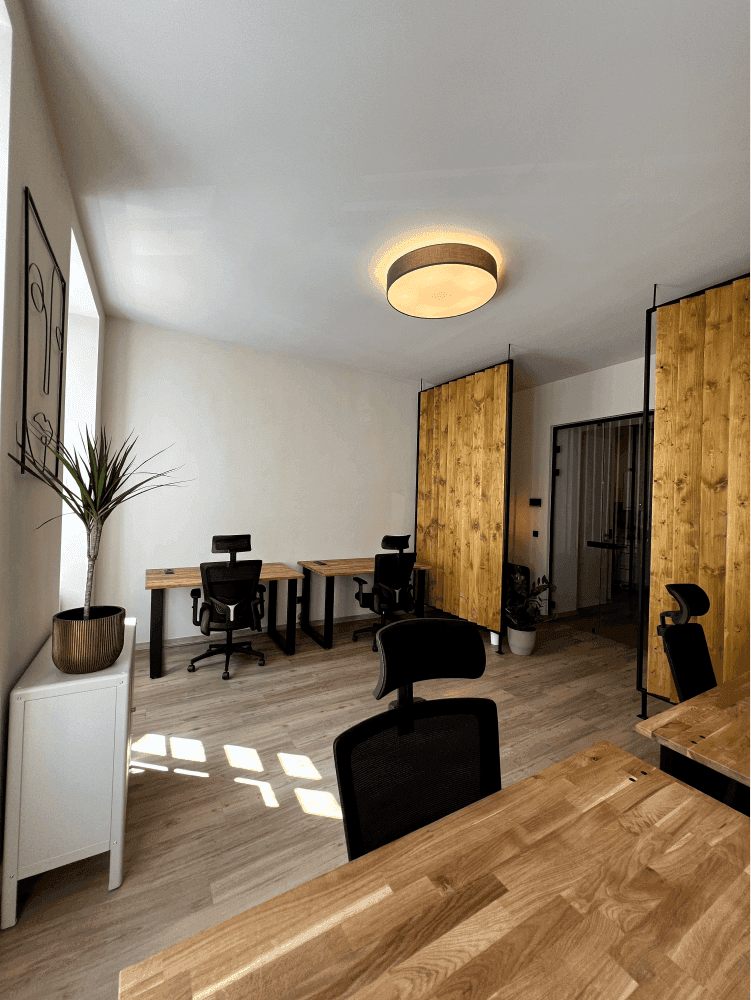 Modernes Büro mit Holztischen, ergonomischen Stühlen und dekorativen Holztrennwänden für eine angenehme Arbeitsatmosphäre.