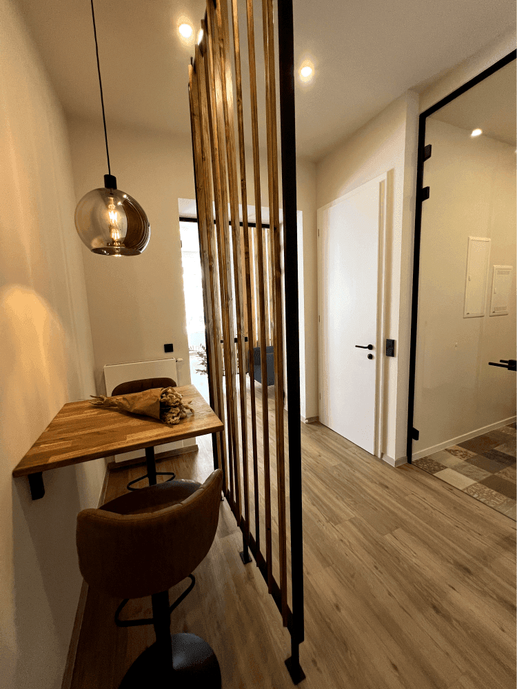 Gemütlicher Nischenbereich im Flur mit Holztisch, Barhocker und moderner Pendelleuchte, ideal für kurze Pausen.