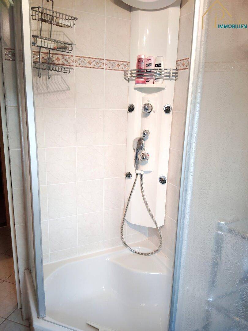 Duschkabine mit integriertem Duschpaneel und Fliesen im Badezimmer.