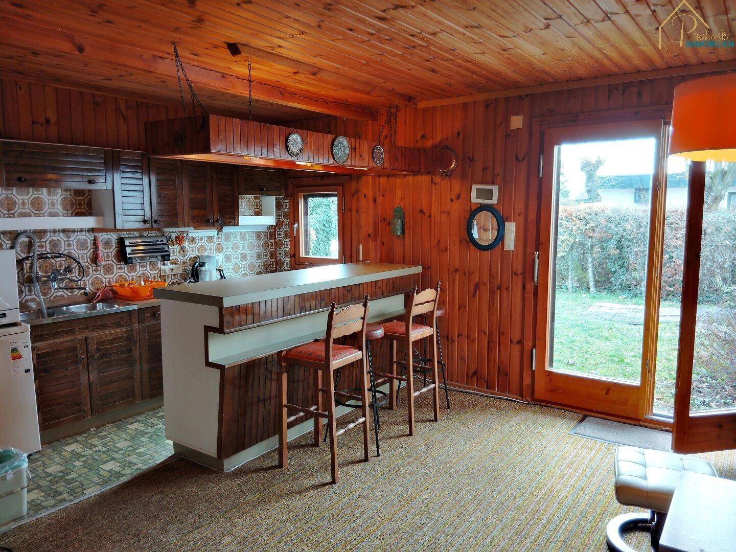 Rustikale Küche mit Holzvertäfelung, Frühstücksbar und Zugang zum Garten.