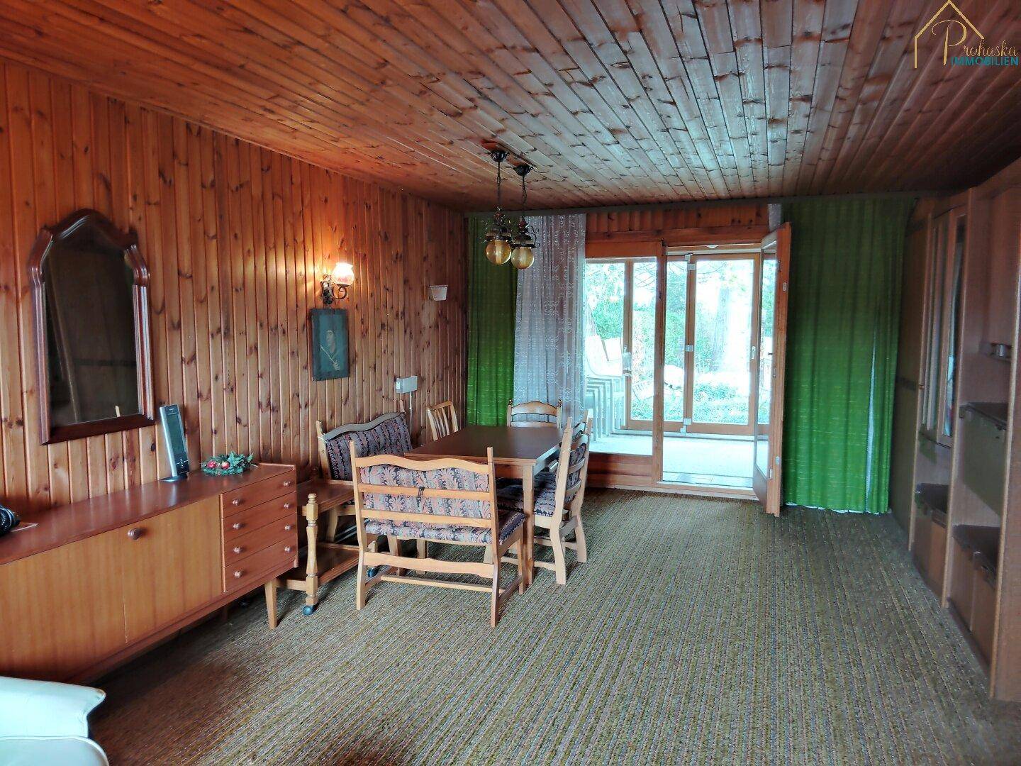 Essbereich mit Holztisch, Stühlen und Zugang zu einem Außenbereich.