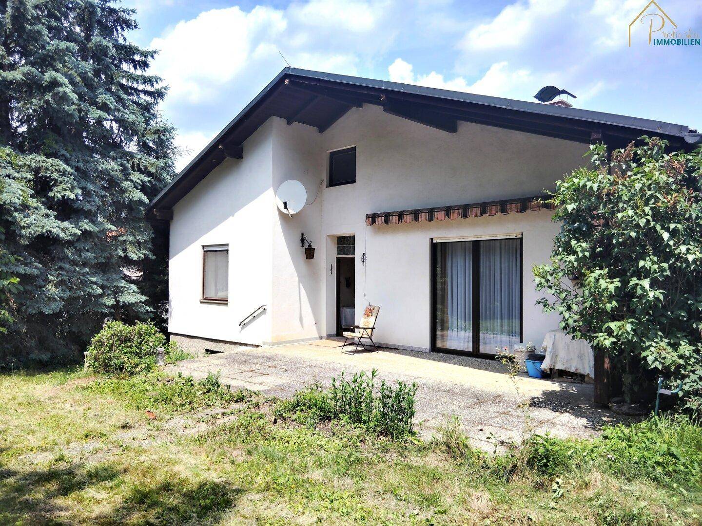 Hausfassade mit sonniger Terrasse und weitläufigem Gartenbereich.