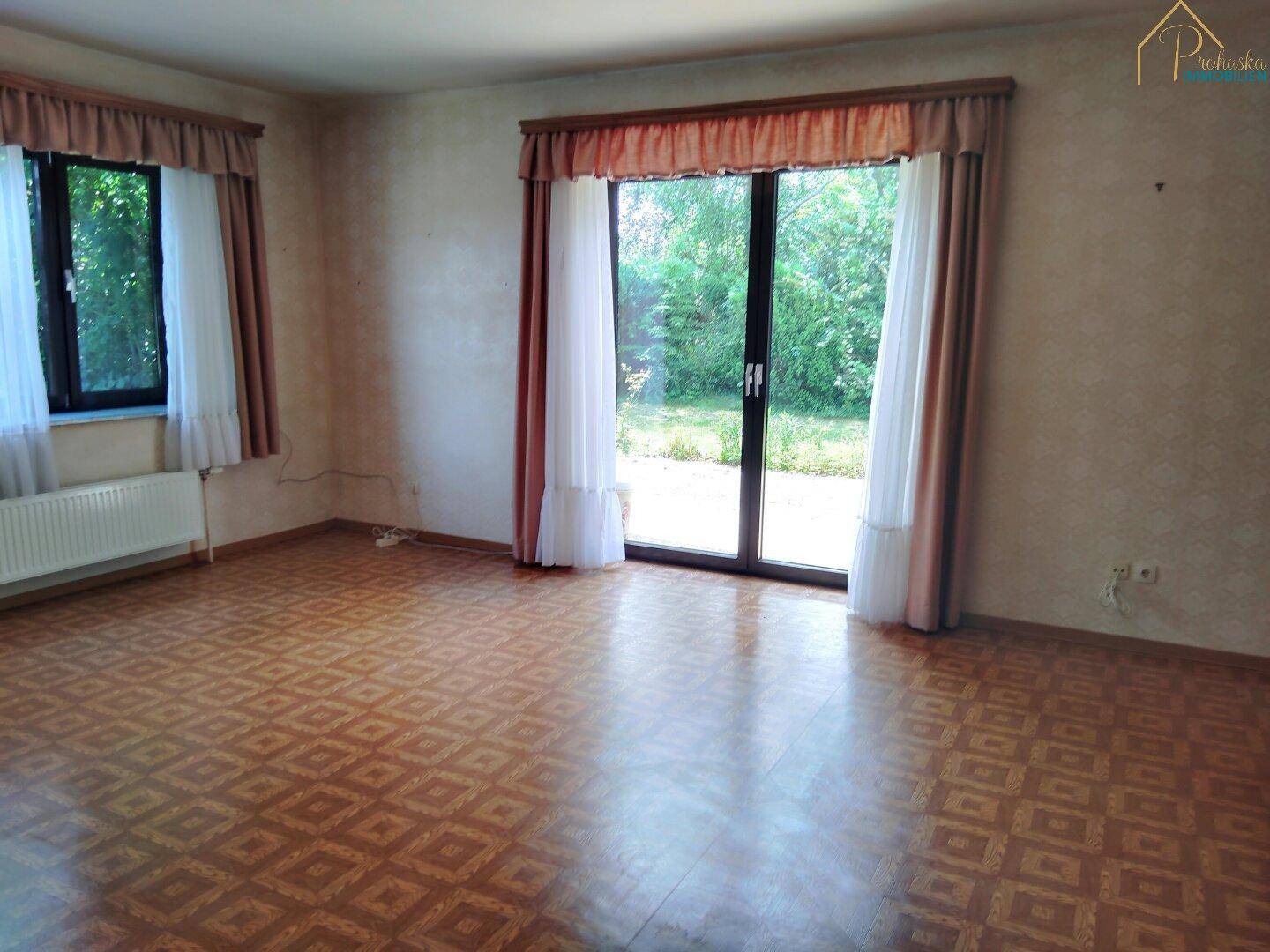 Helles Wohnzimmer mit großem Fenster und direktem Zugang zum Garten.