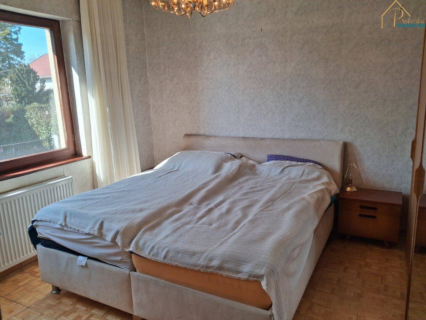 Schlafzimmer mit Doppelbett, Nachttisch und Parkettboden.