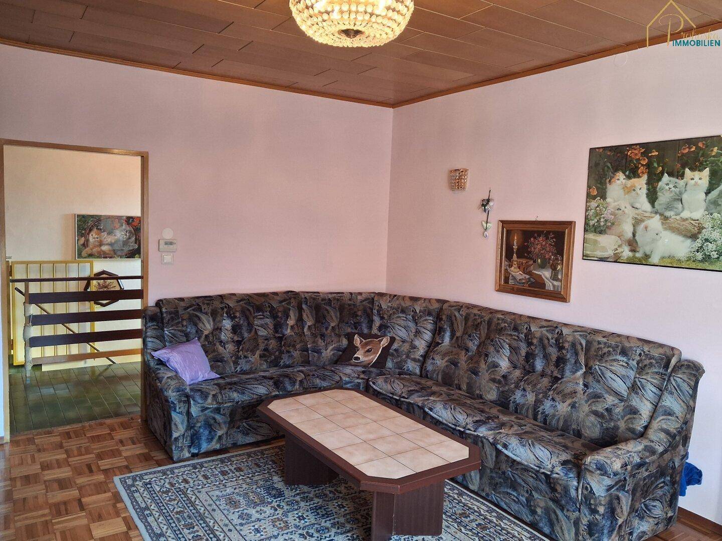 Geräumiges Wohnzimmer mit Ecksofa, Parkettboden und Holzdecke.