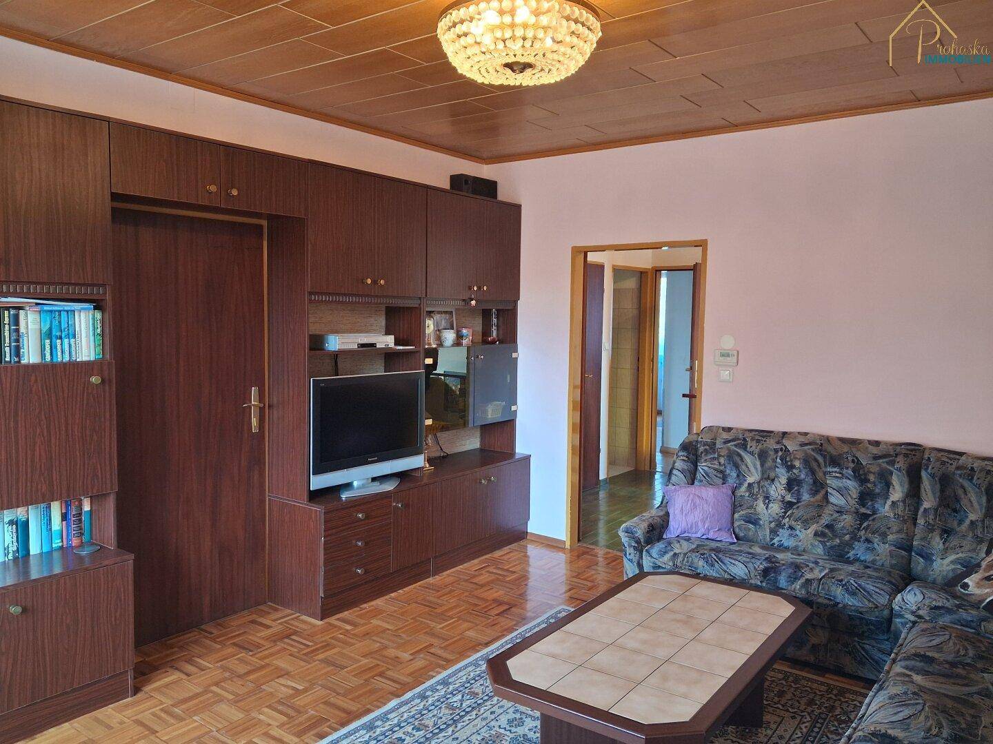 Gemütliches Wohnzimmer mit Holzdecke, Parkettboden und großem Wandschrank.