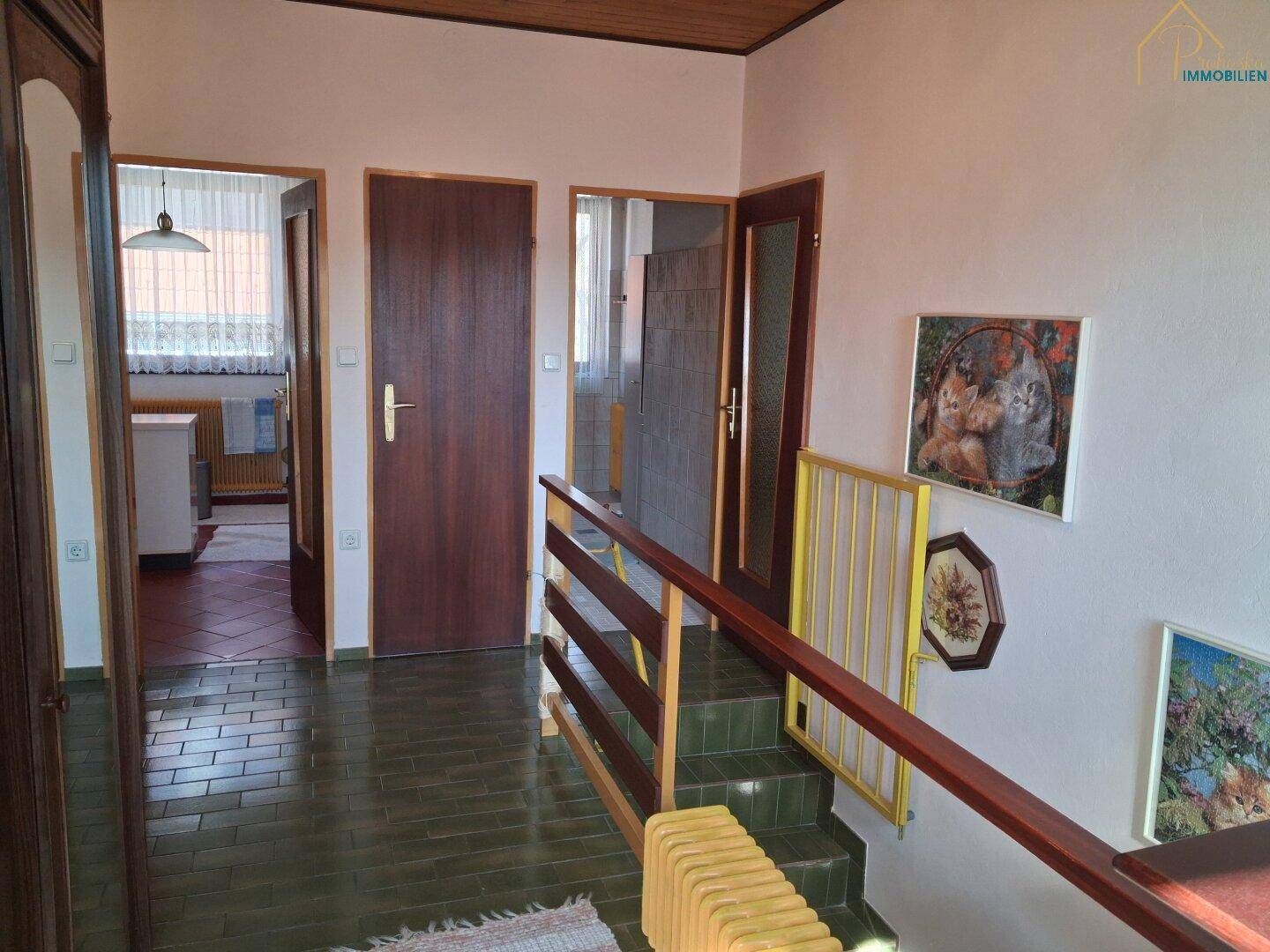 Flur mit Treppe, Fliesenboden und Zugang zu weiteren Räumen.