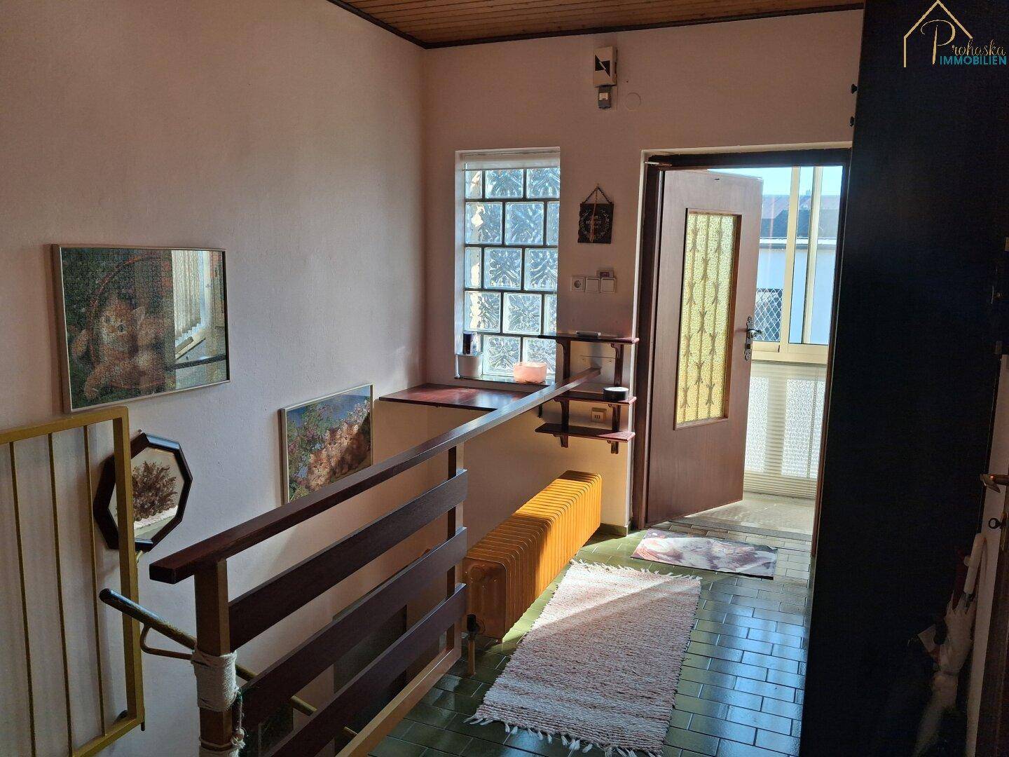 Heller Eingangsbereich mit Treppe, Fliesenboden und Fenster.